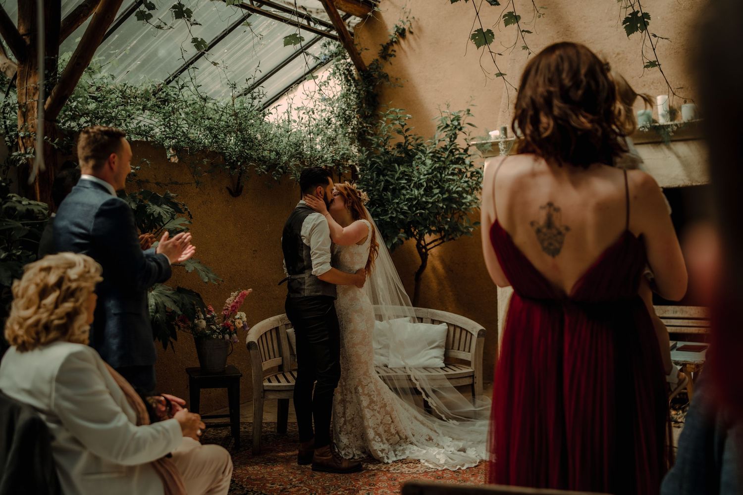 Wedding guests mingle and celebrate during an outdoor reception under string lights at sunset.