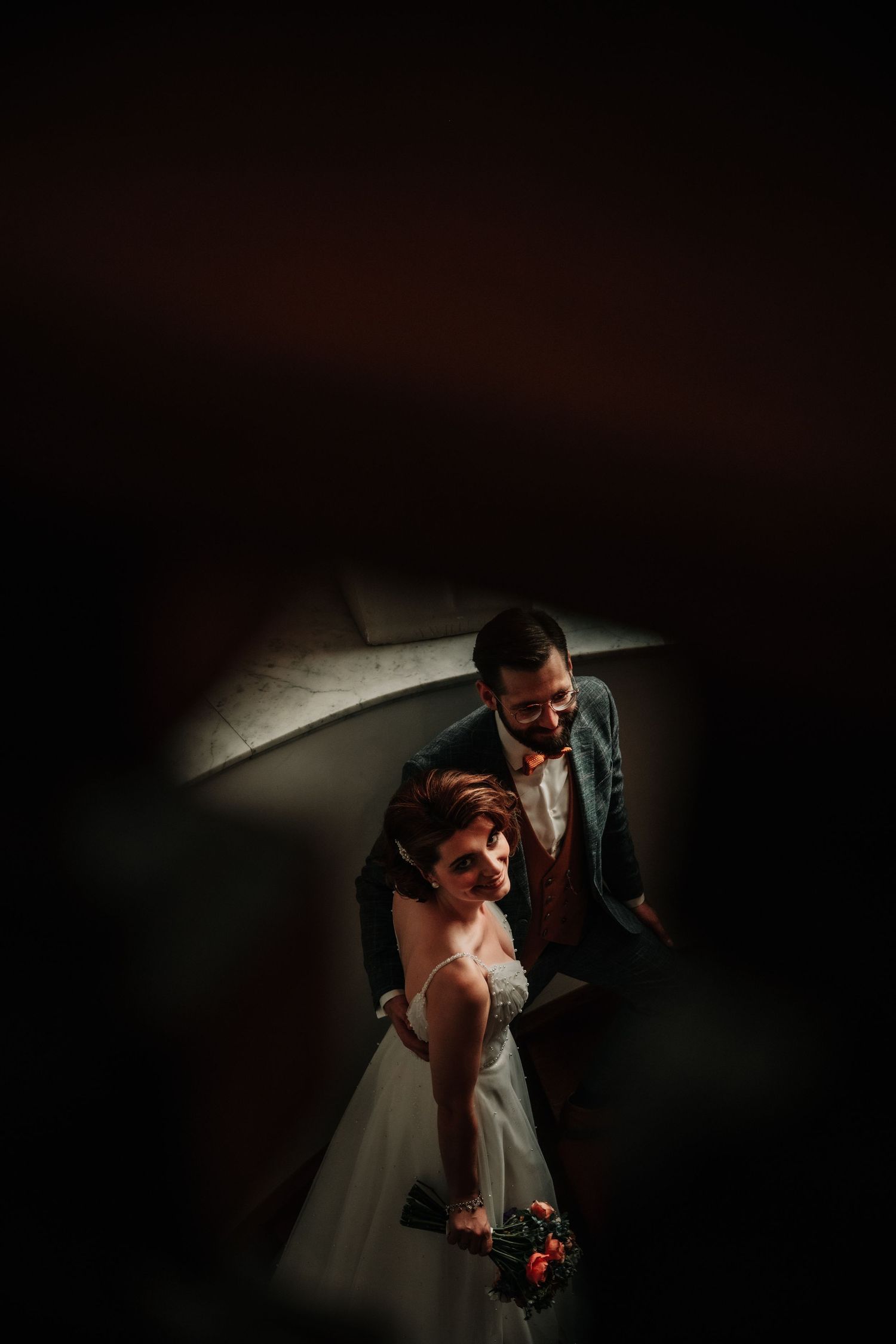 Wedding couple in dramatic lighting share an intimate moment during their reception.