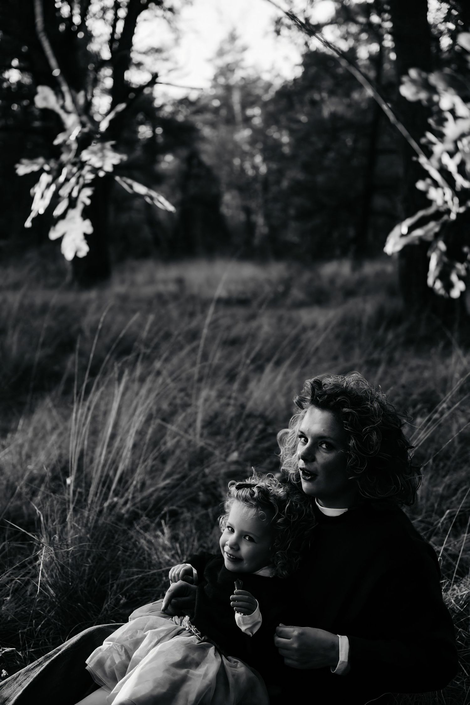 Black and white portrait of people laying in tall grass looking up at the sky.