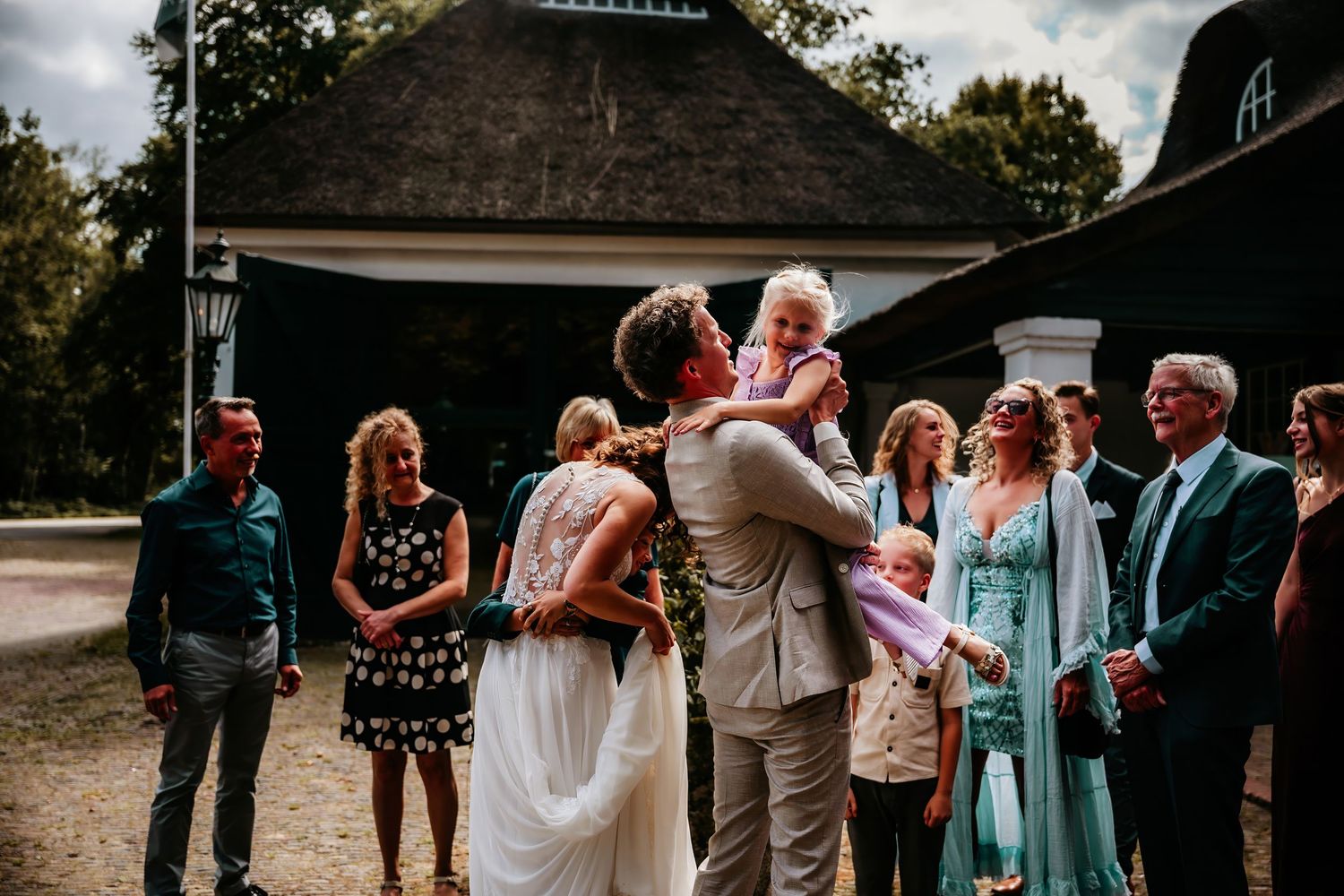 Wedding celebration with guests gathered outdoors near a rustic building.