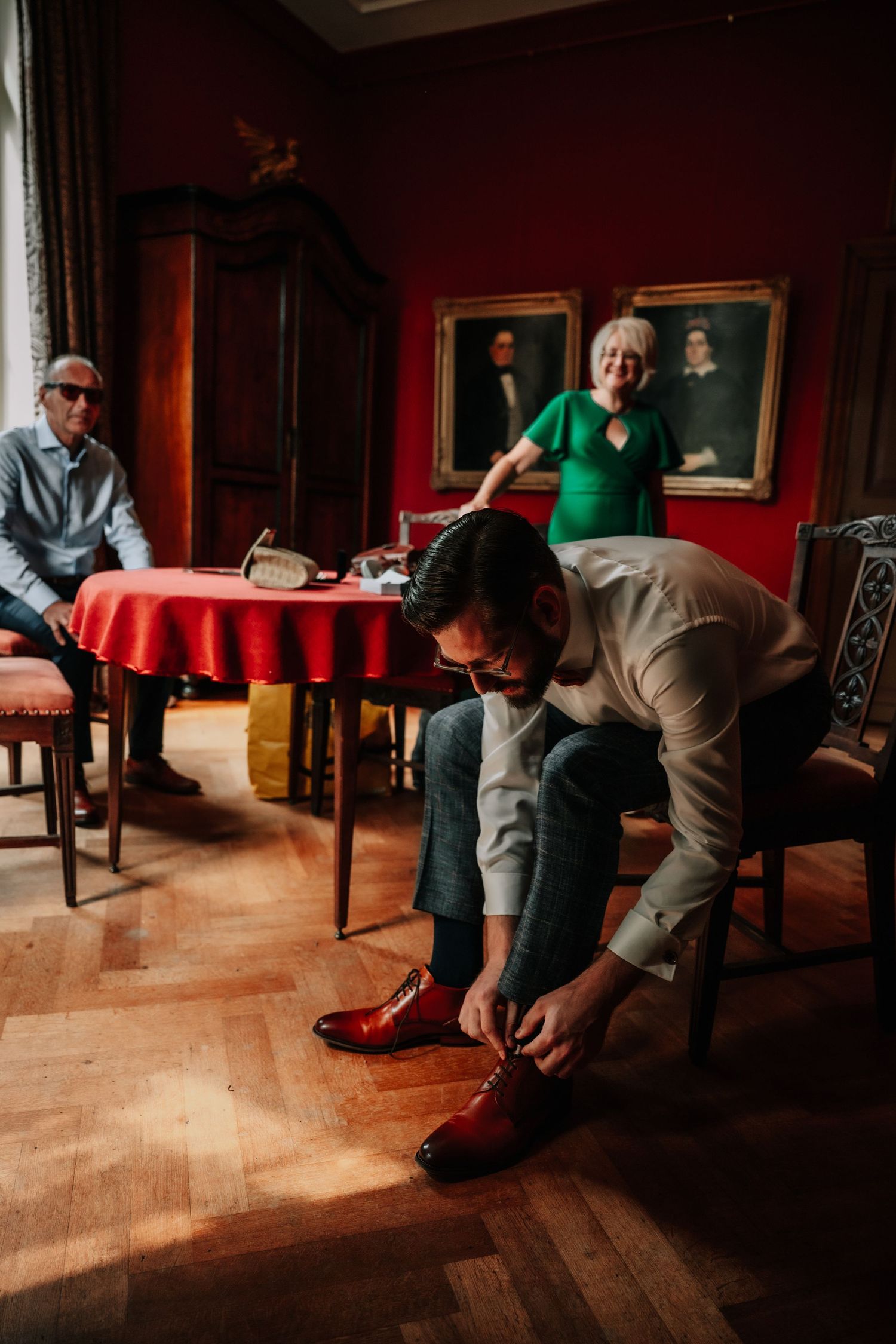 Getting ready in a dimly lit room with red walls and wooden floors.