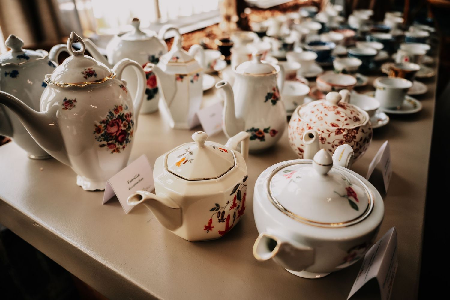 Collection of vintage teapots and china displayed on a white surface in soft natural light.