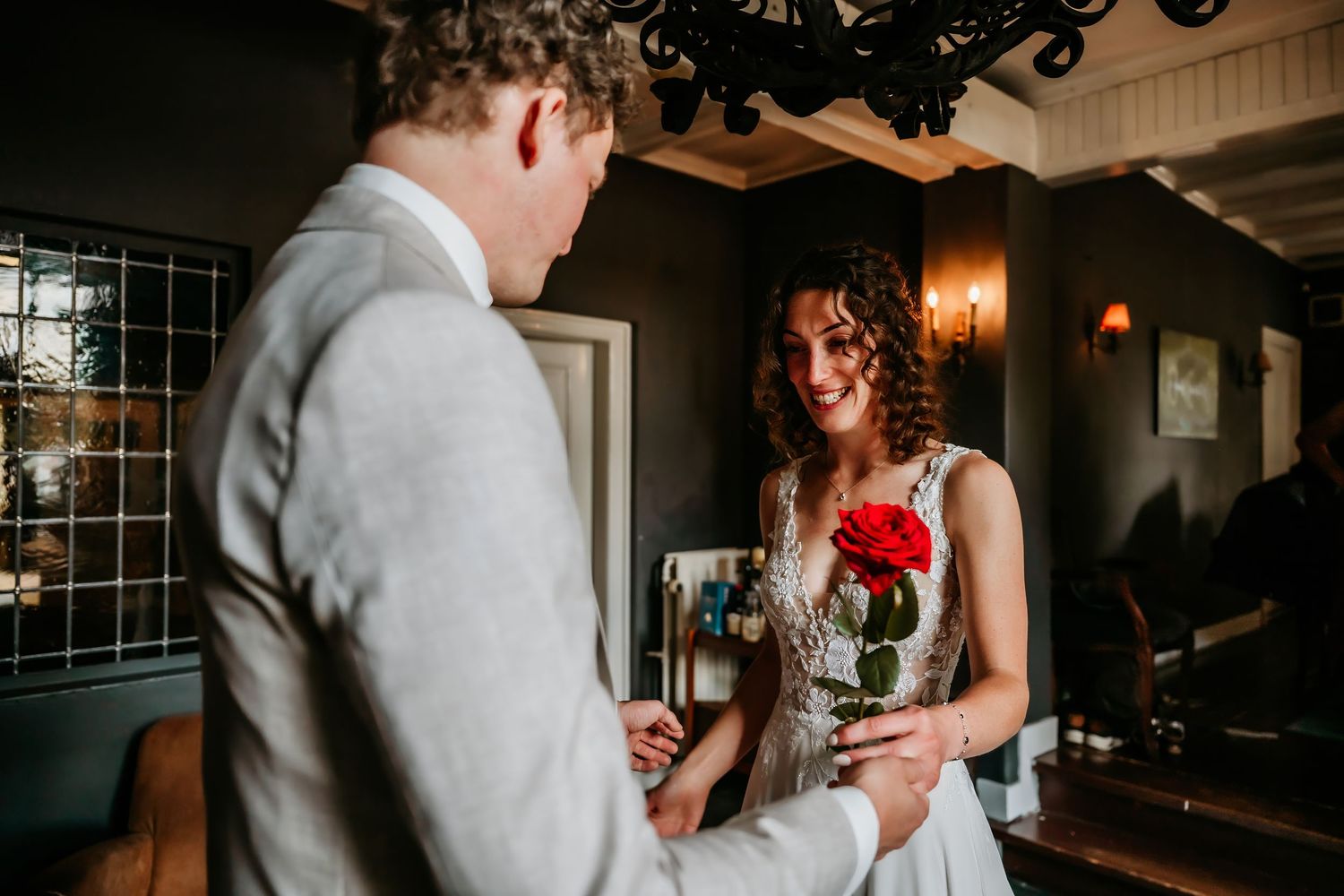 A couple shares an intimate moment during their wedding ceremony as they exchange rings in a dimly lit indoor venue.