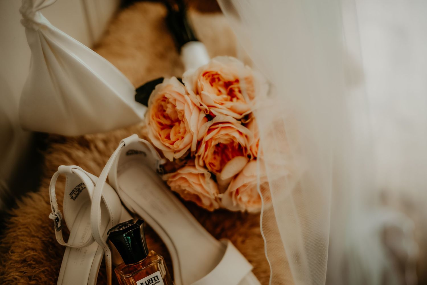 Delicate peach roses and white flowers arranged with soft fabric in a romantic wedding setting.