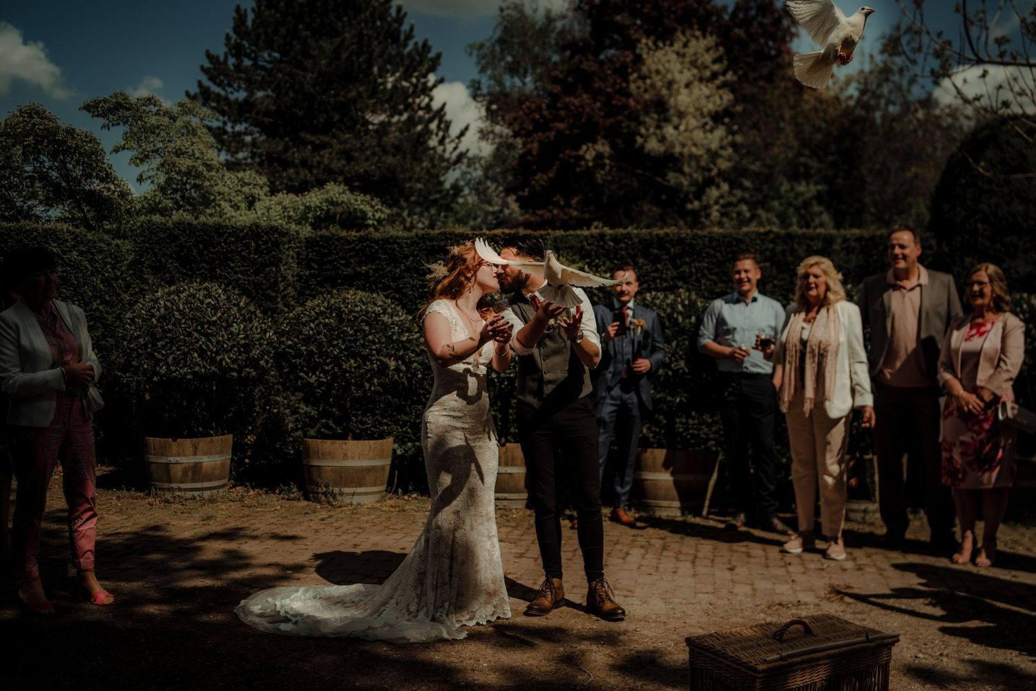 Outdoor wedding celebration in a sunlit garden with natural landscaping.