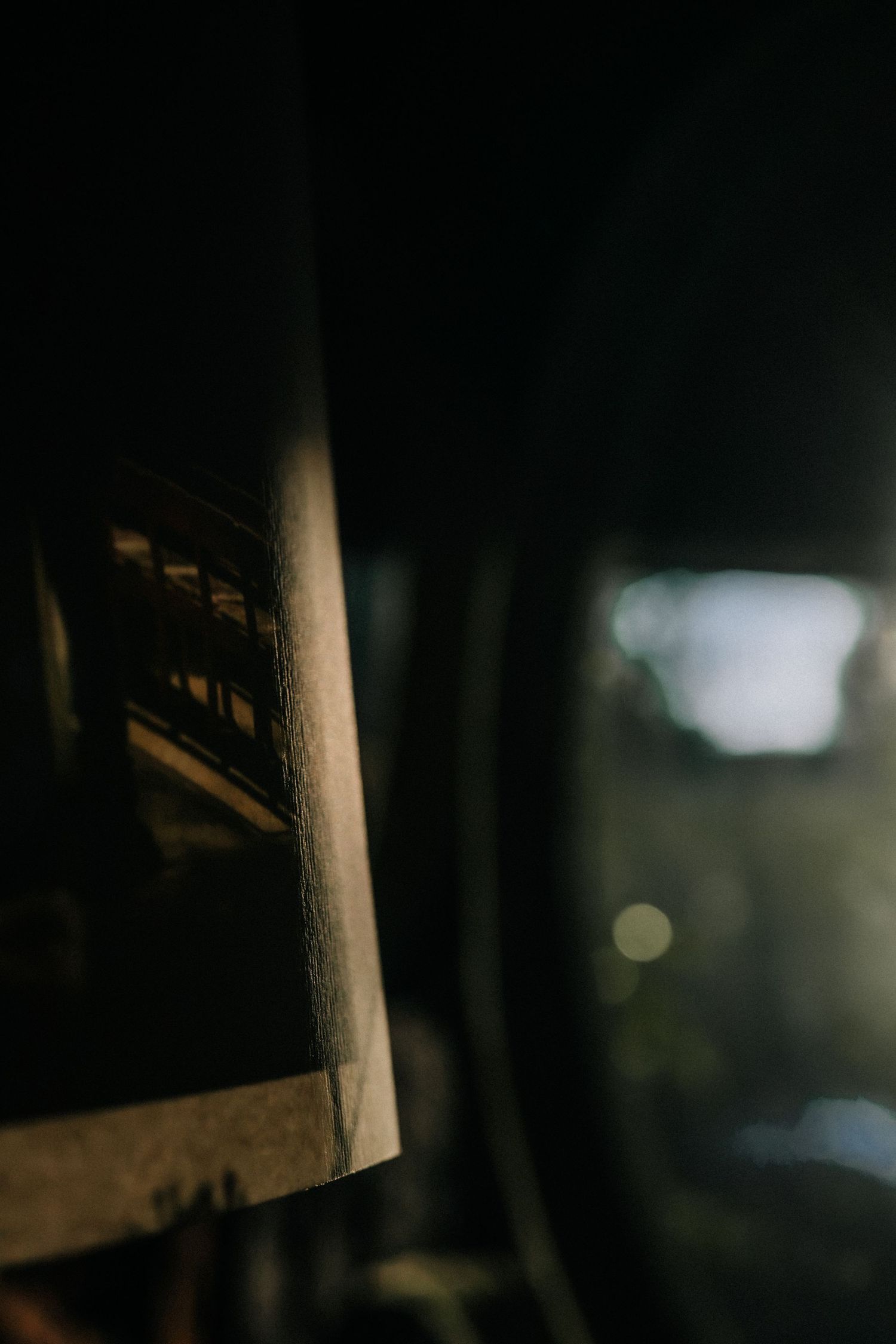 Dark moody photograph of a vintage photo leaning against a wall with blurred bokeh lights in the background.