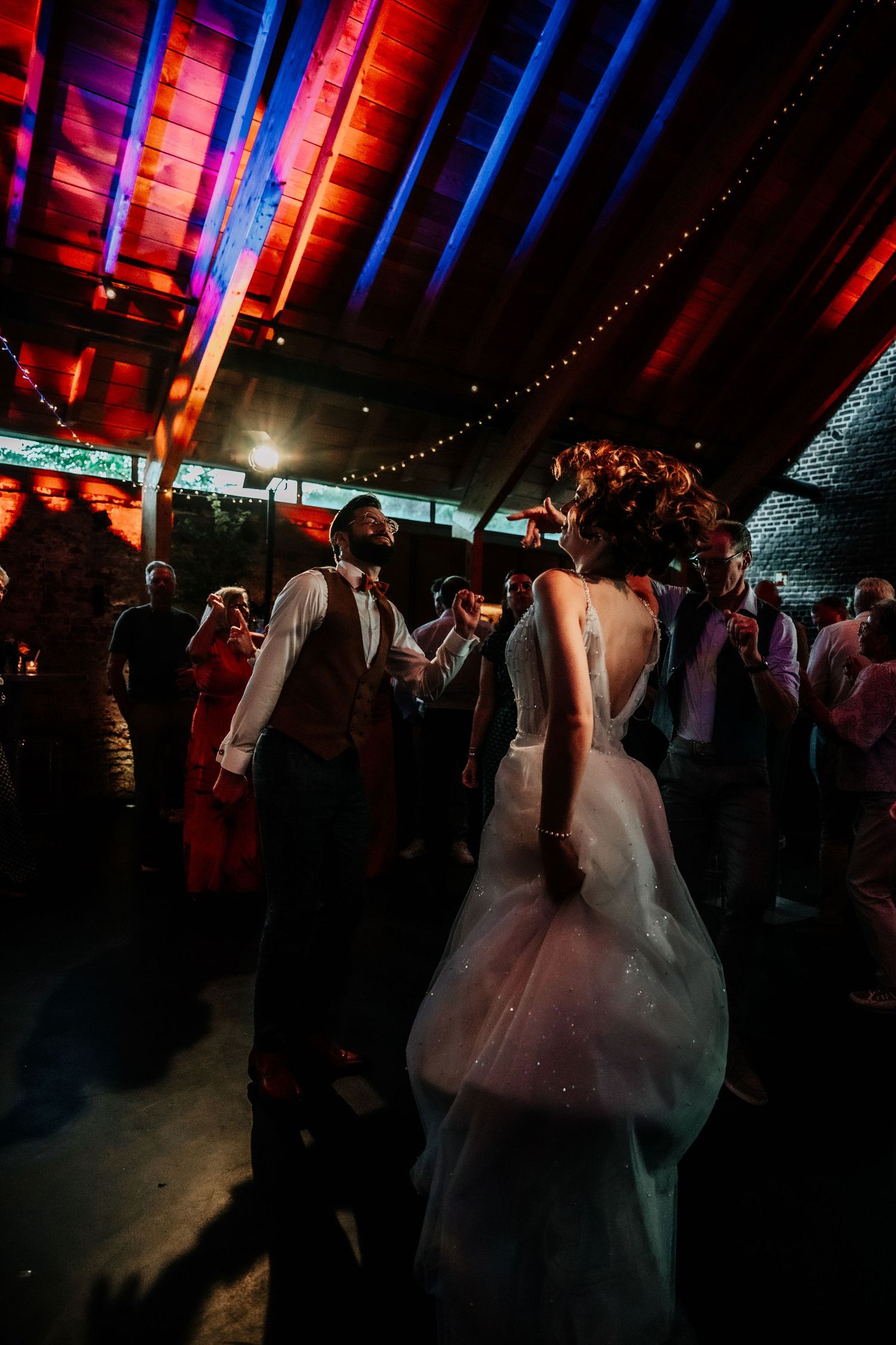 Wedding celebration in a dimly lit barn with dramatic blue and red lighting effects.