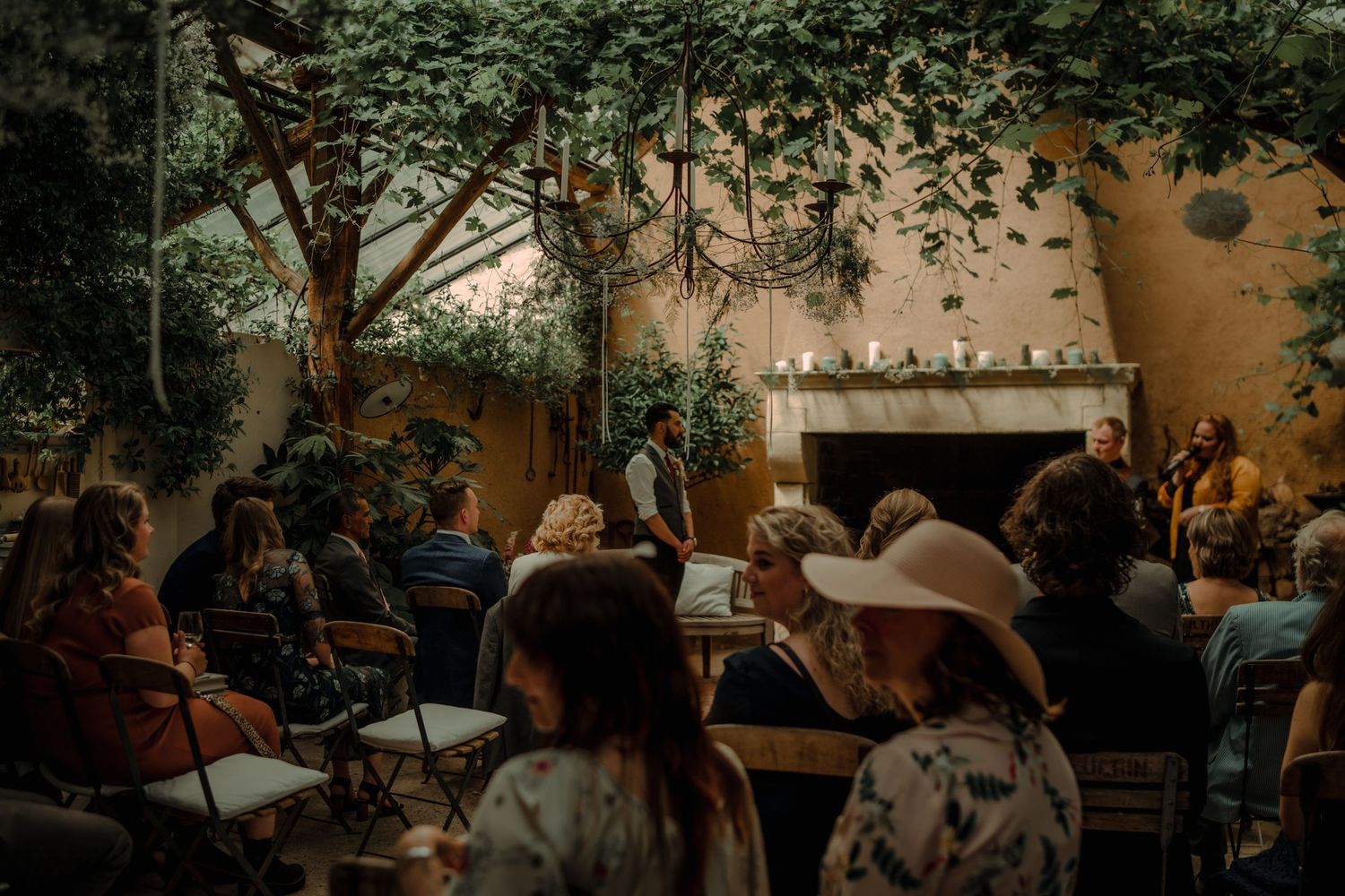 Guests seated in an intimate outdoor garden ceremony space with string lights overhead.