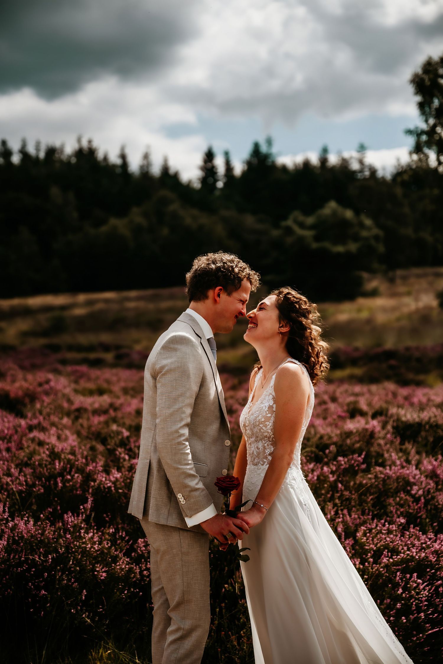 Wedding couple sharing an intimate moment in a field of purple heather under moody skies.