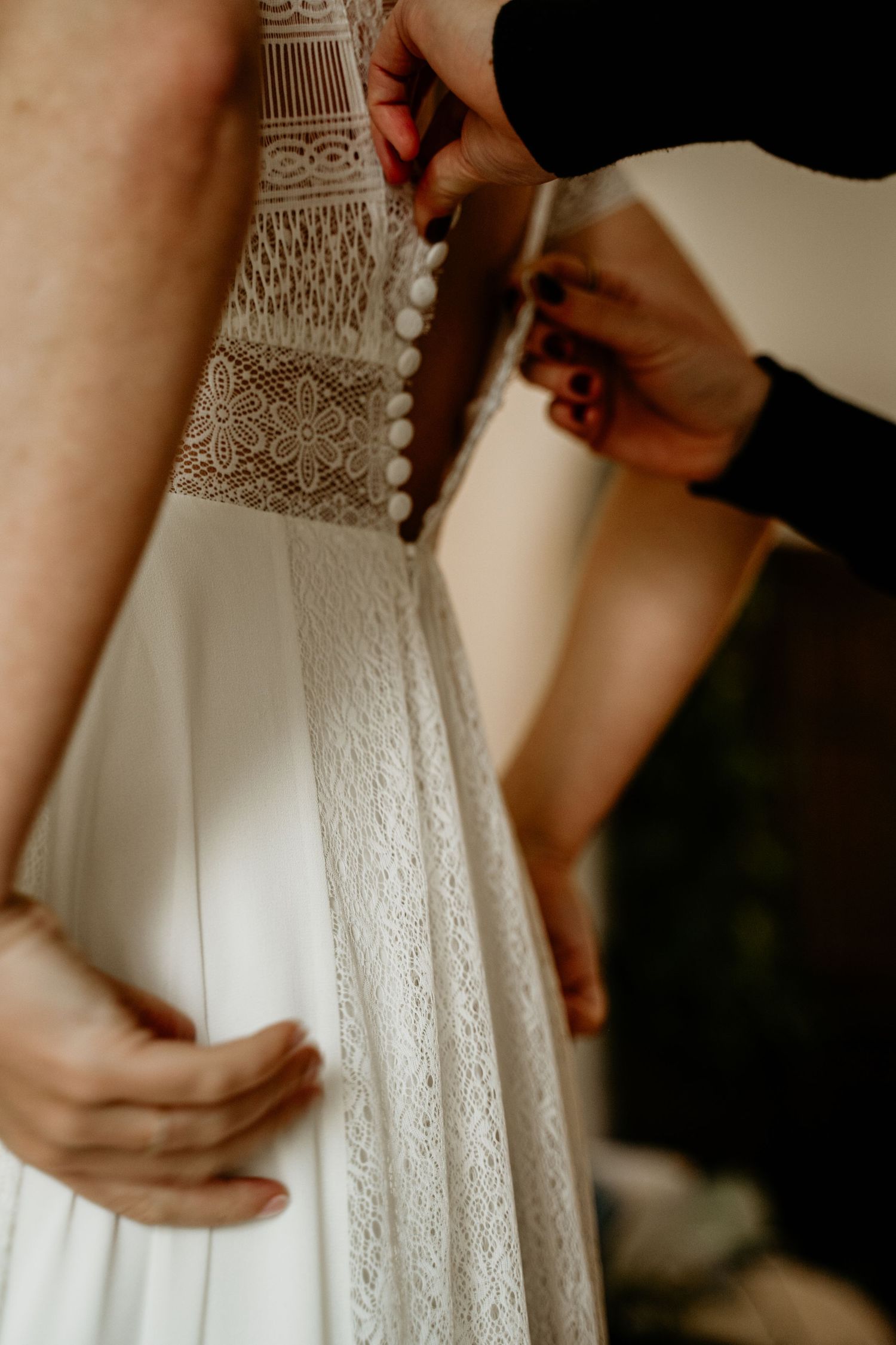 Close-up shots showing the delicate details and buttons of a white lace wedding dress.