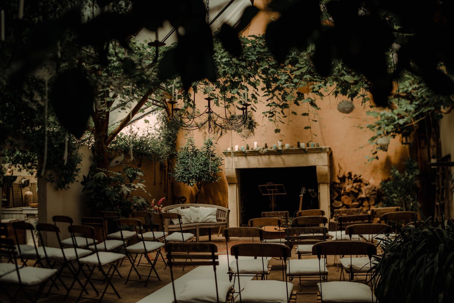 Intimate outdoor wedding venue setup with folding chairs and string lights in a garden courtyard at dusk.