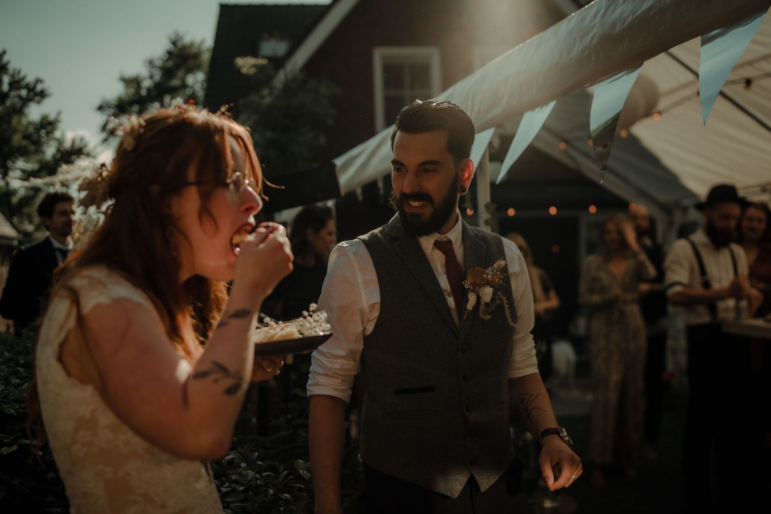 Wedding celebration under white umbrellas during golden hour outdoors.