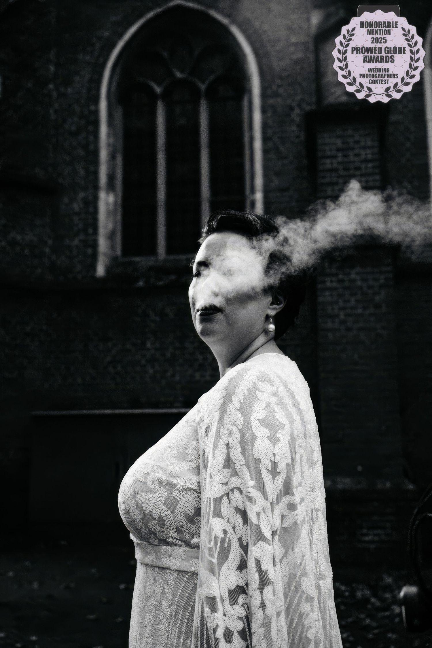 A black and white artistic portrait shows a figure in white lace clothing exhaling smoke against a dark background.