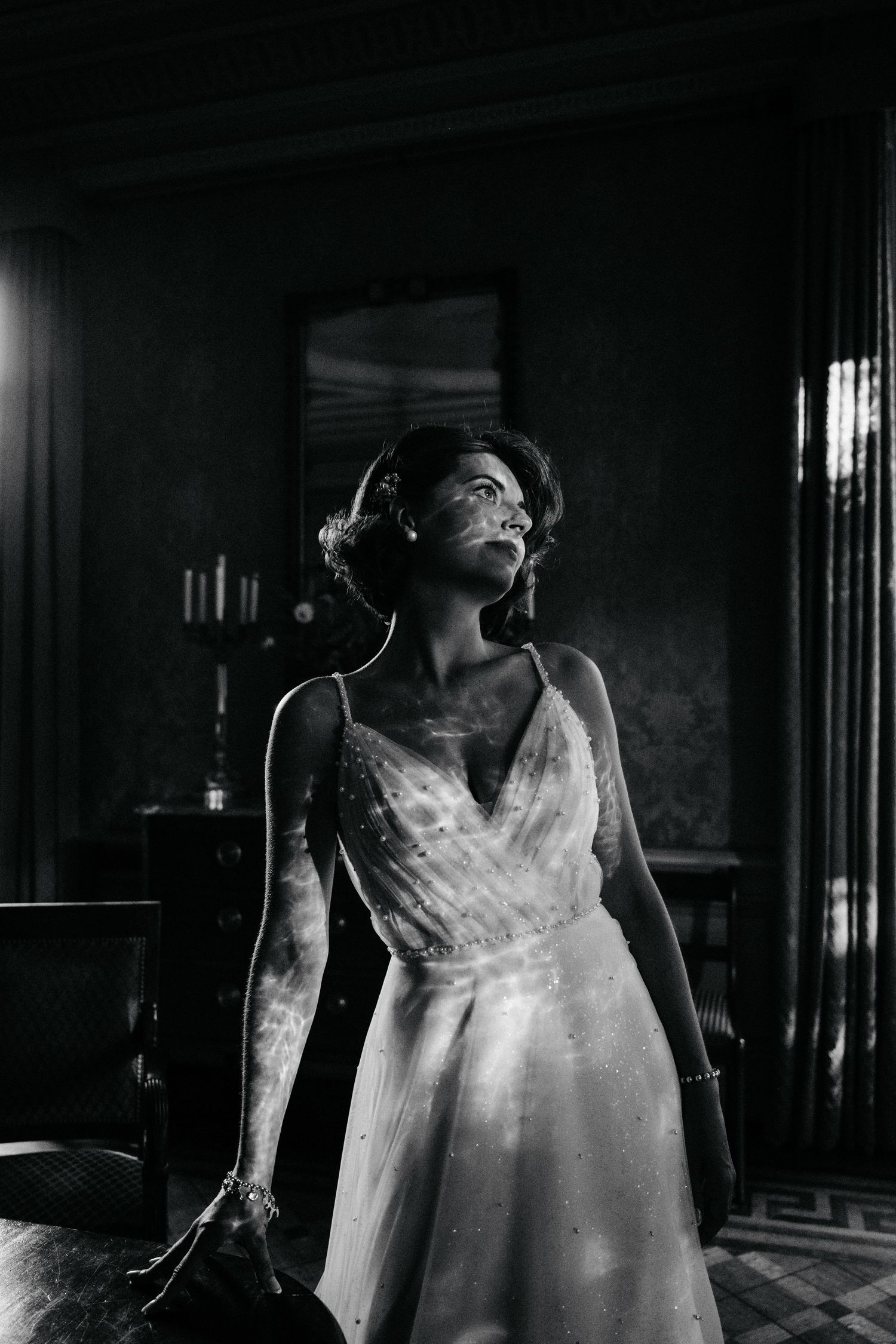 Elegant white wedding dress silhouetted in dramatic black and white lighting.