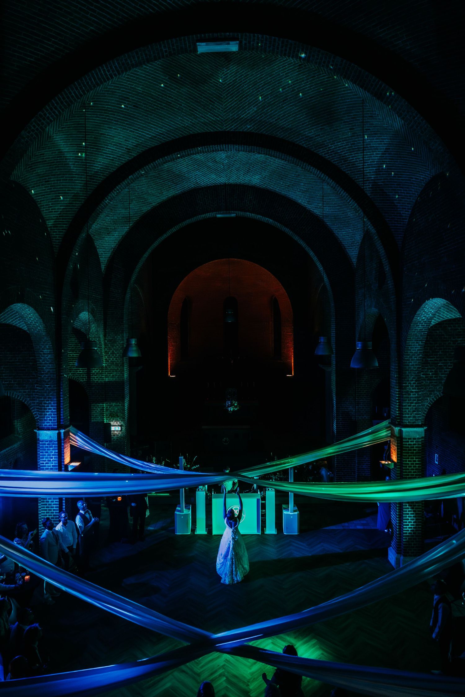 A sequence of light painting photographs showing glowing blue and green light streaks in a dark stone tunnel or archway.