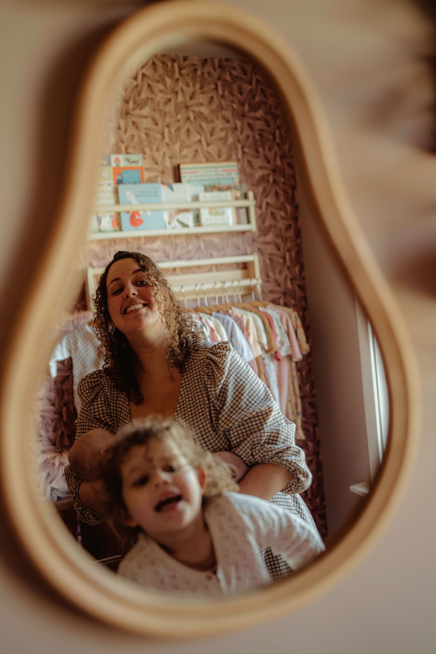 Mirror reflection captures playful nursery moment with patterned wallpaper.