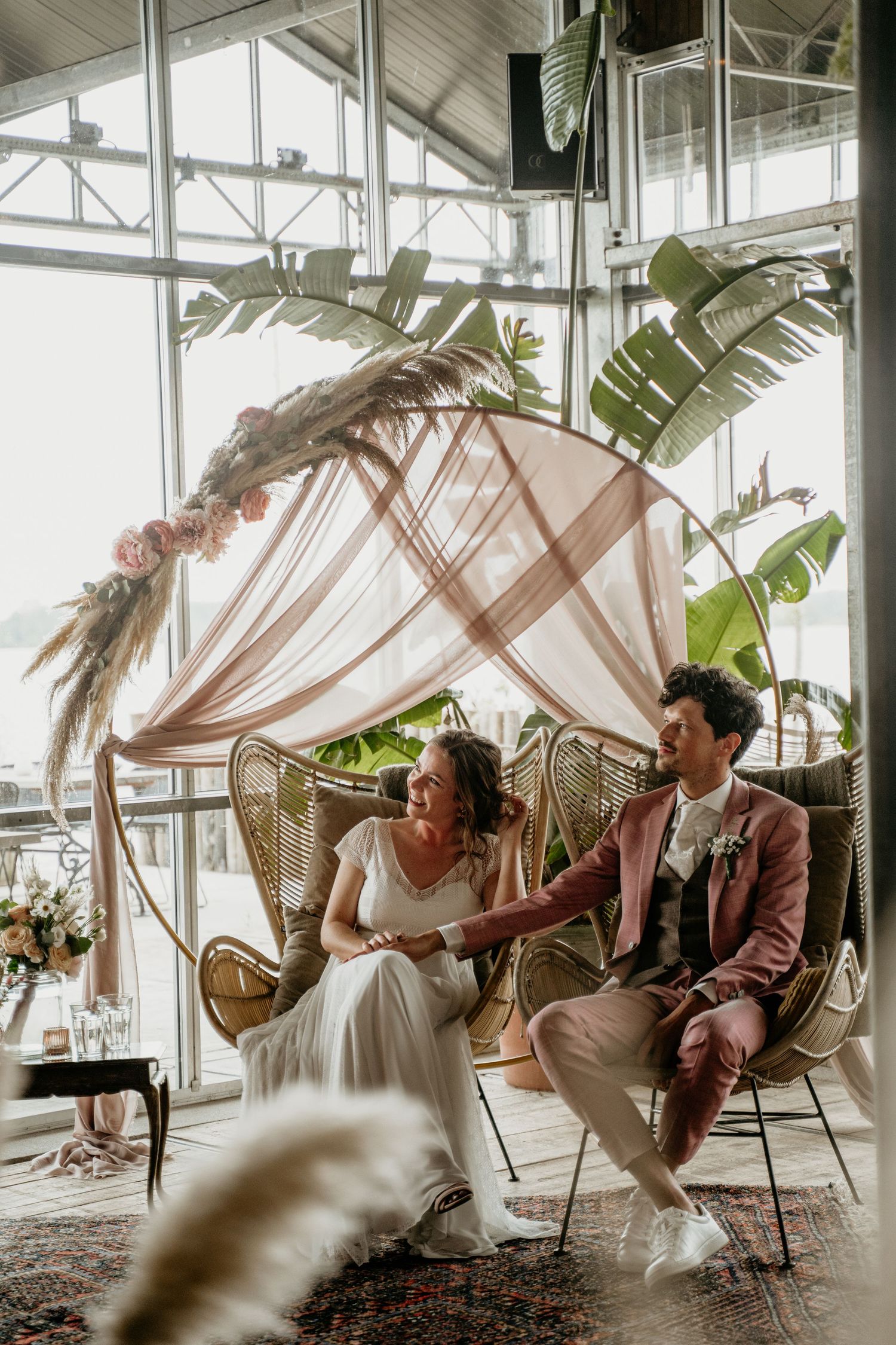 Modern greenhouse venue with white hanging decorations and tropical plants.