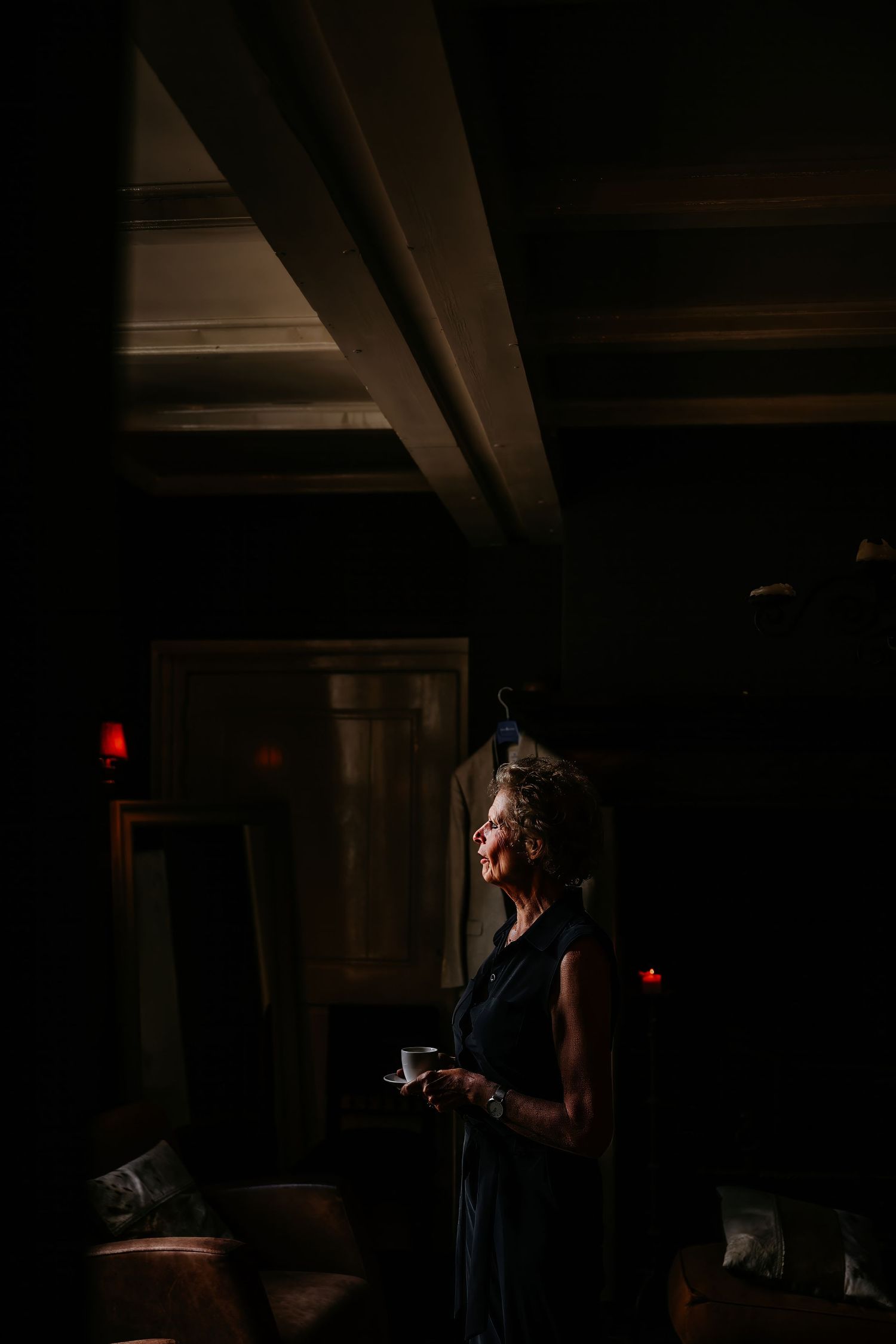 Dramatic silhouette of a person standing in a dimly lit interior space with dramatic window lighting.