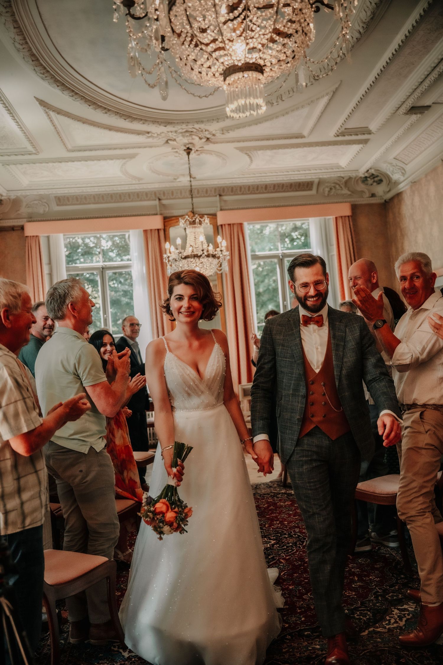 Elegant wedding reception in a room with ornate ceiling and large windows.
