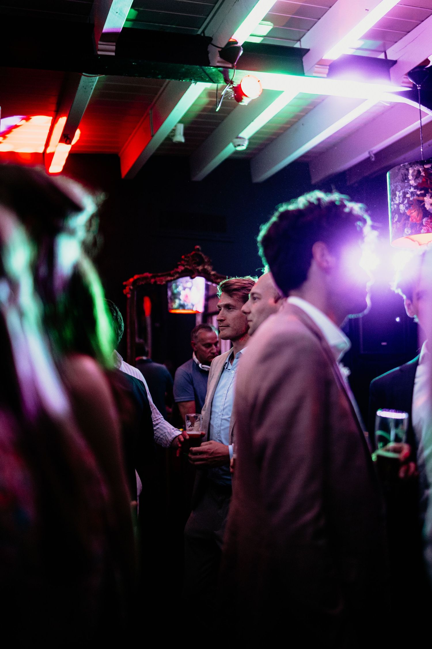 Colorful nightclub scene with neon lights illuminating crowd of party-goers.