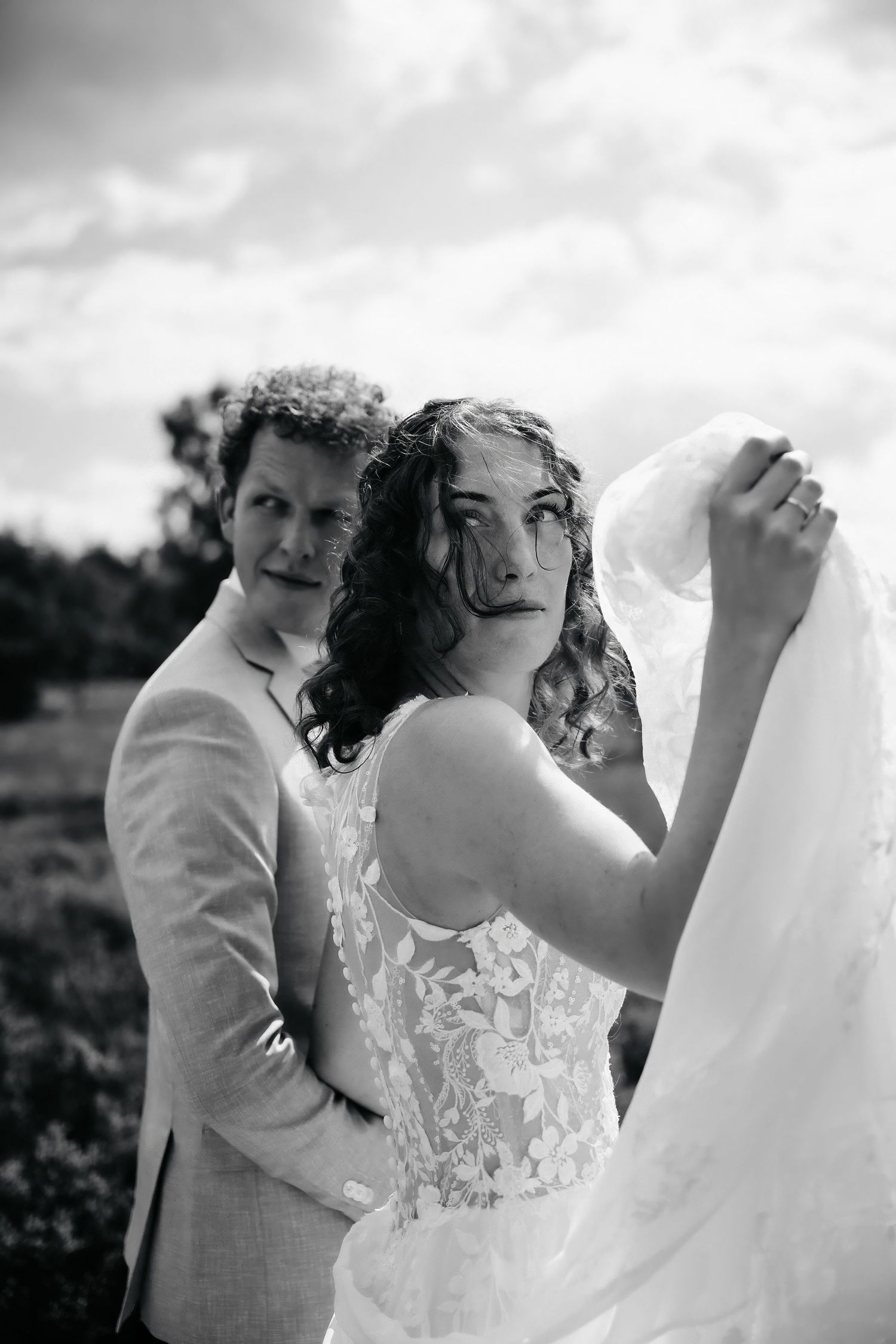 A joyful wedding moment captured in black and white as the couple shares a laugh during their outdoor celebration.