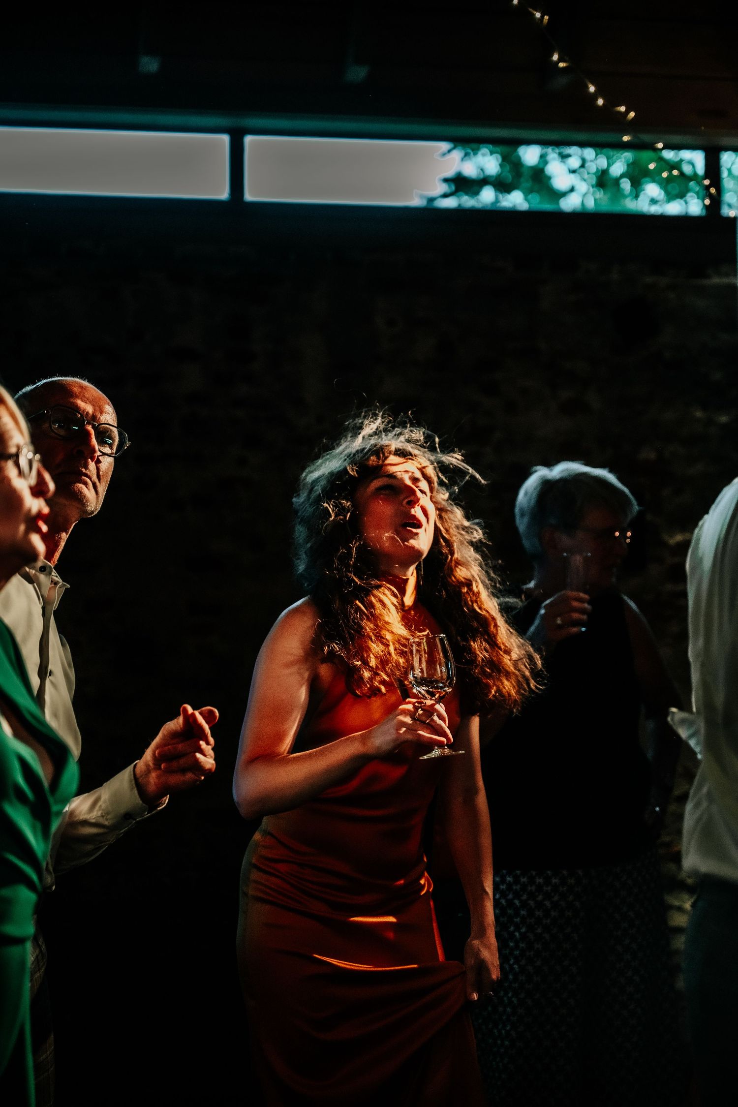 Couples dancing together in dramatic lighting at an evening wedding reception.