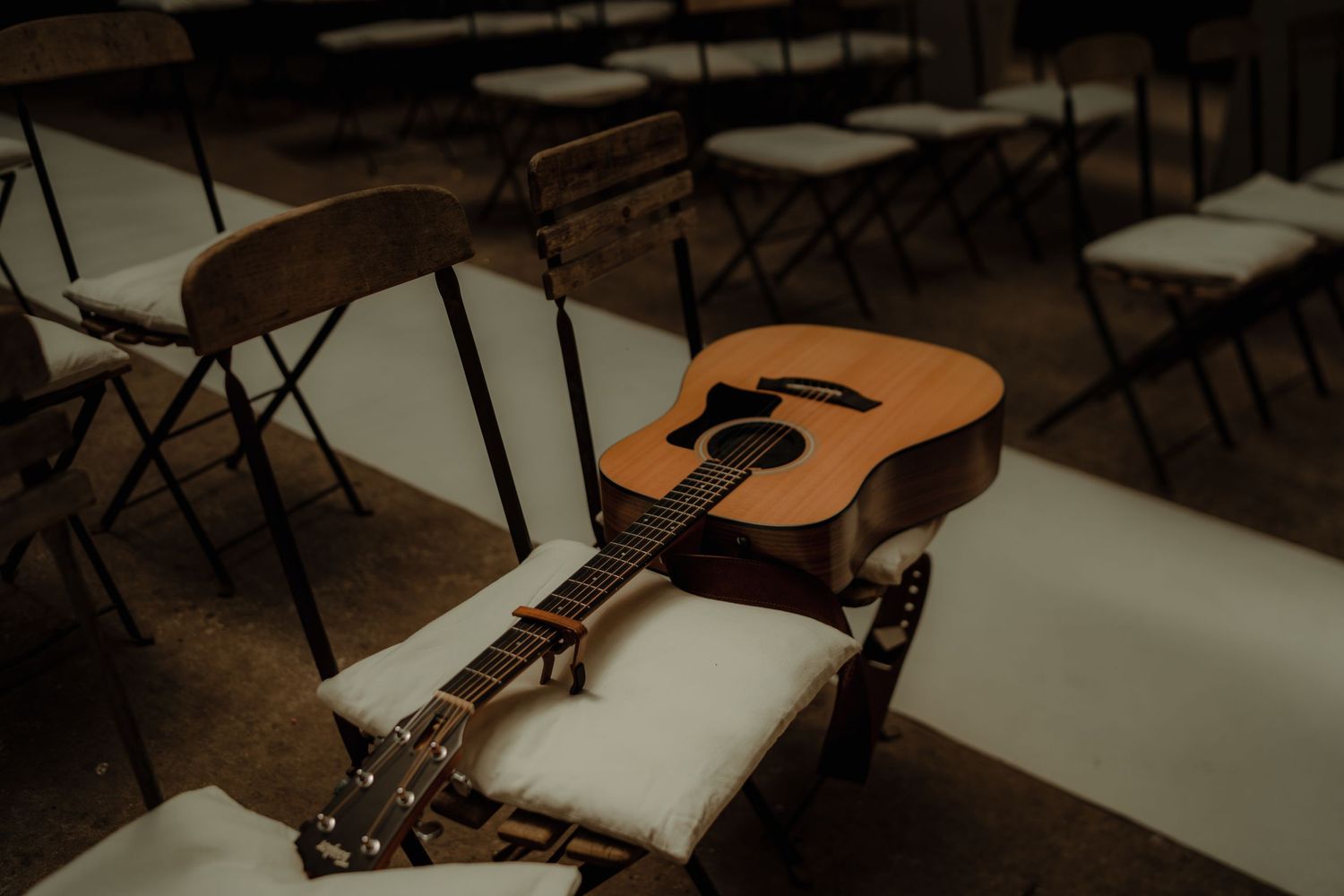 Acoustic guitar resting on chairs at an outdoor wedding venue setup.