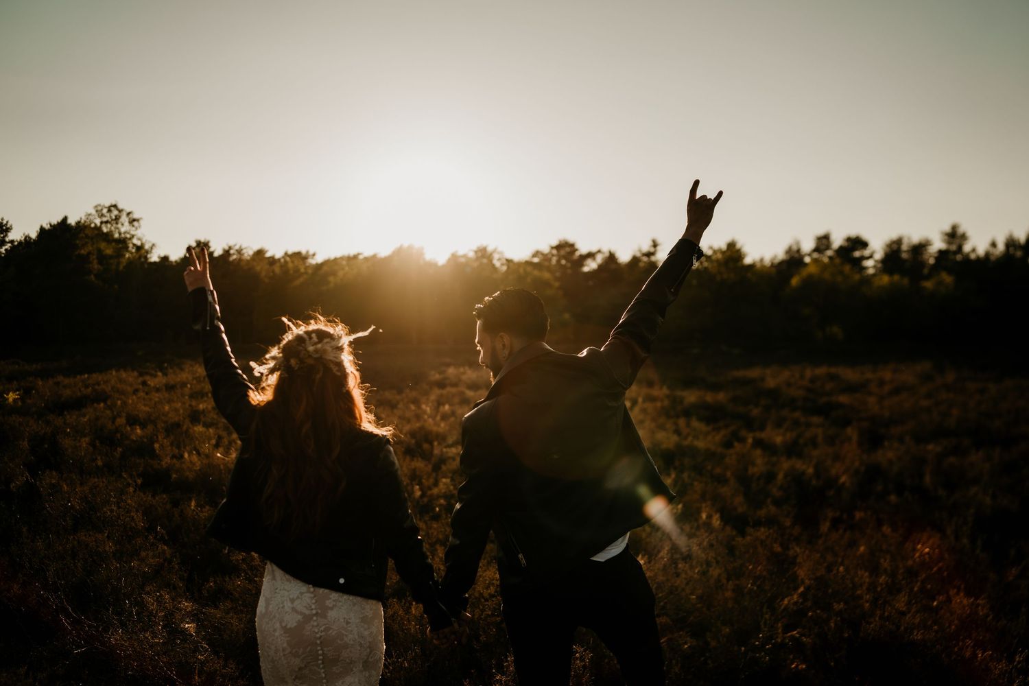 Two silhouettes raising their arms in celebration against a sunset backdrop.