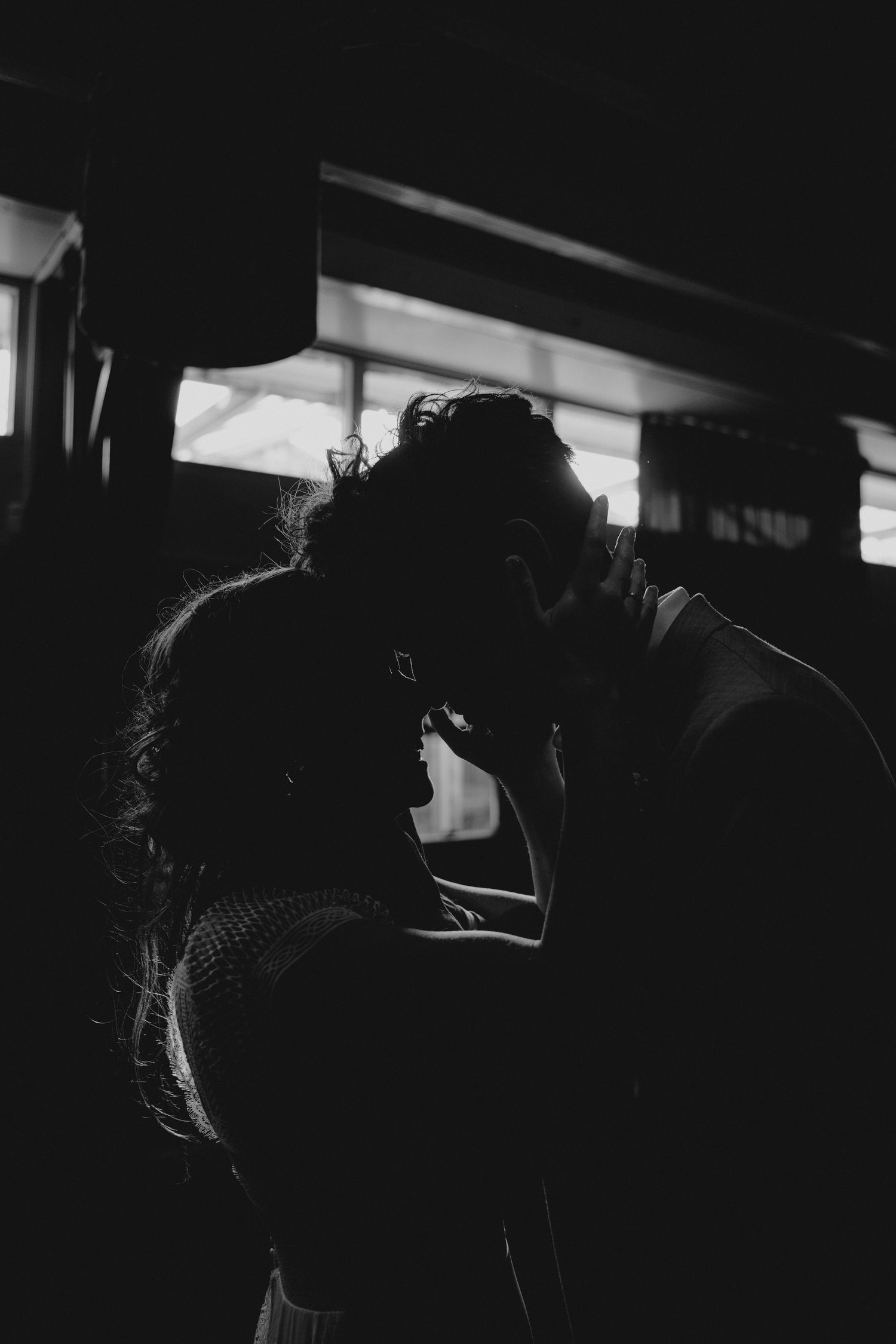 A dramatic black and white silhouette of a couple in an intimate embrace.