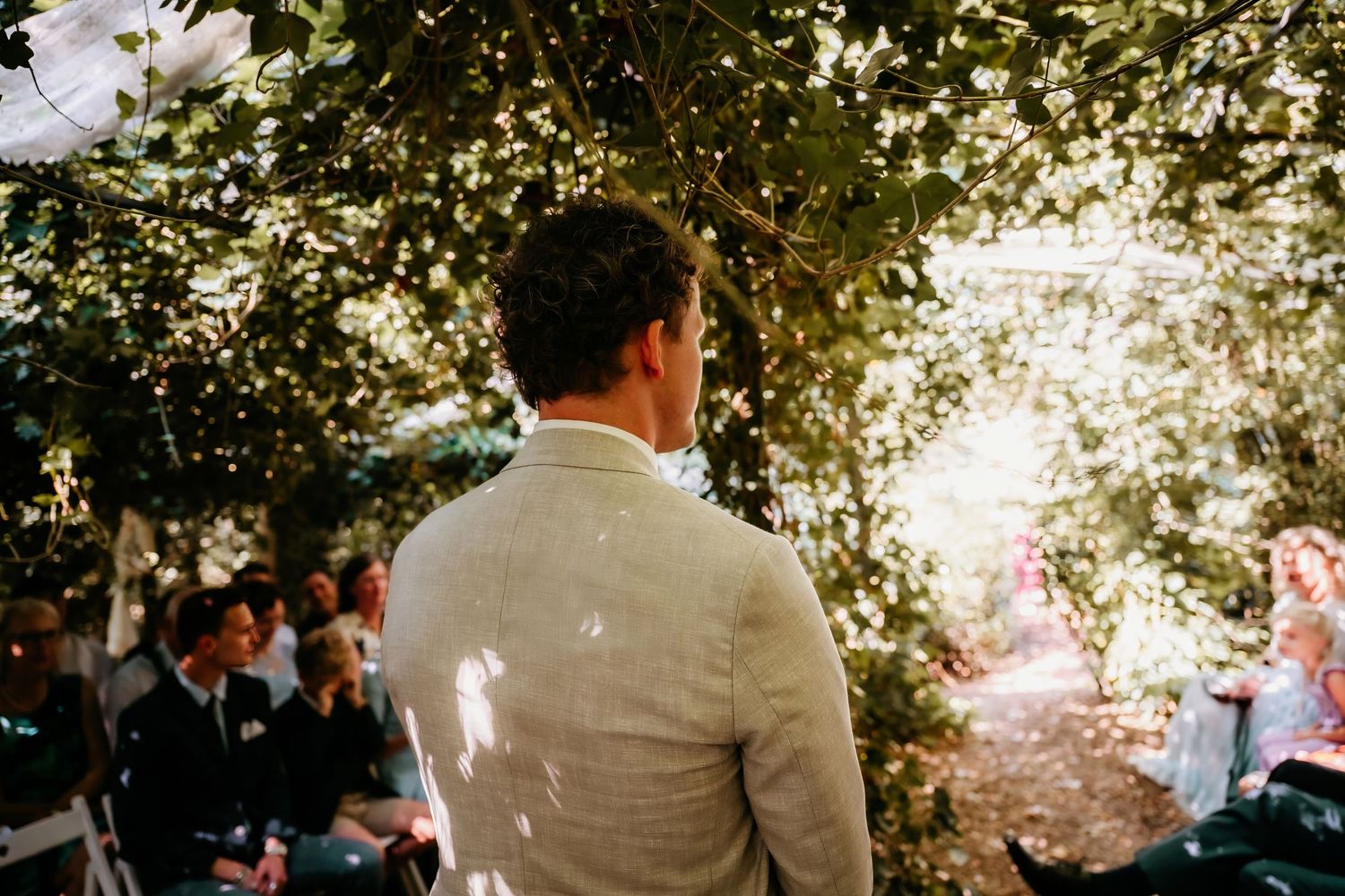Sunlight filters through tree branches during an outdoor wedding ceremony.