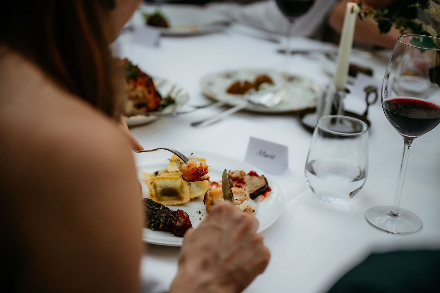 Elegant wedding reception table settings with wine glasses and place cards.