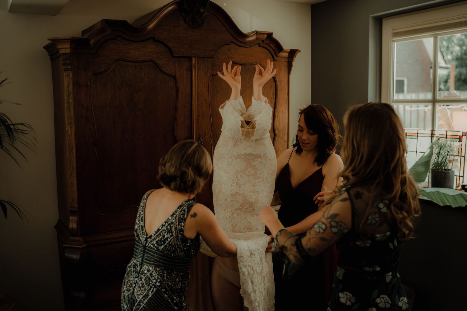 People gathered in a dimly lit room sharing an emotional moment during what appears to be a wedding celebration.