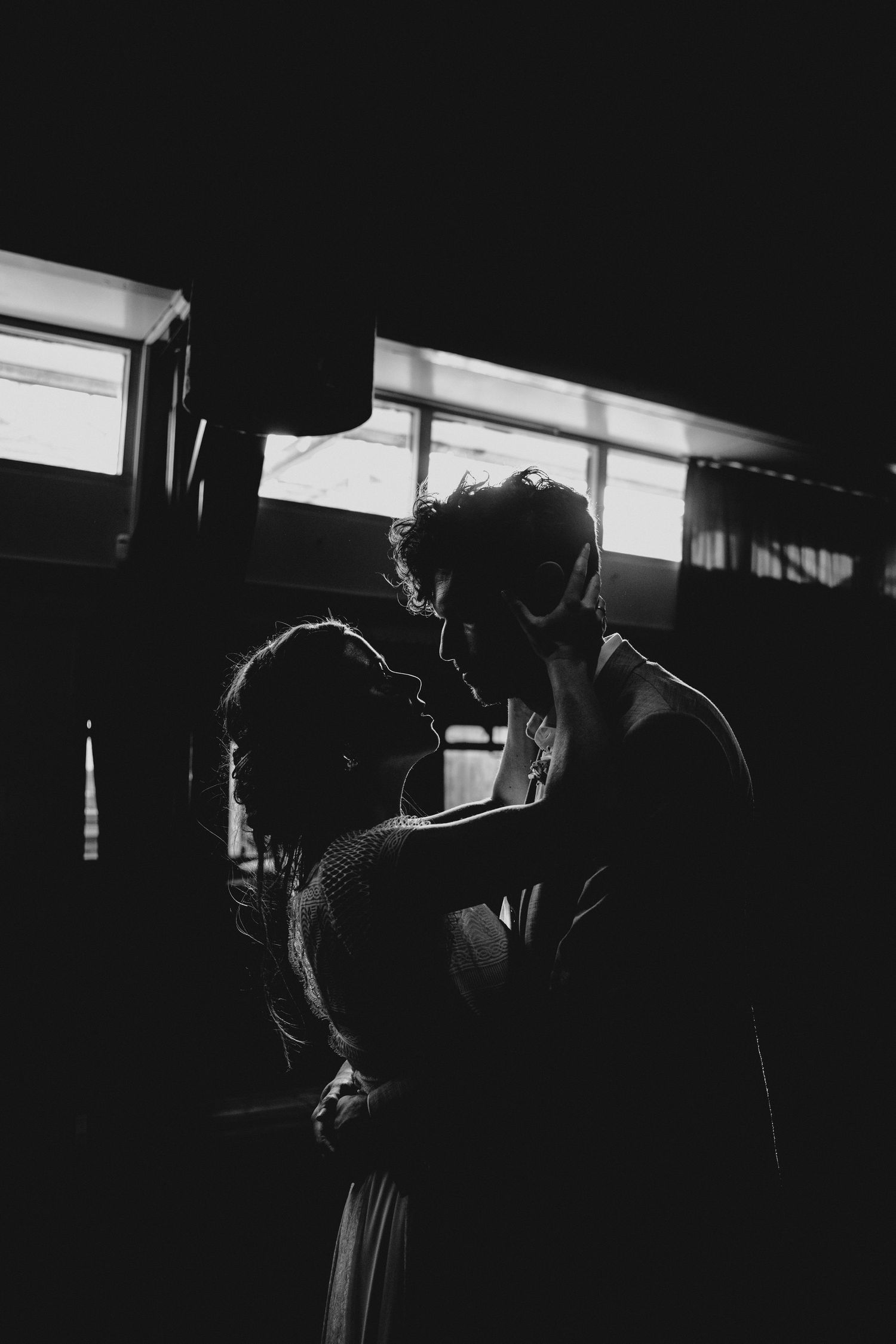 A silhouetted couple embraces in dramatic window lighting.