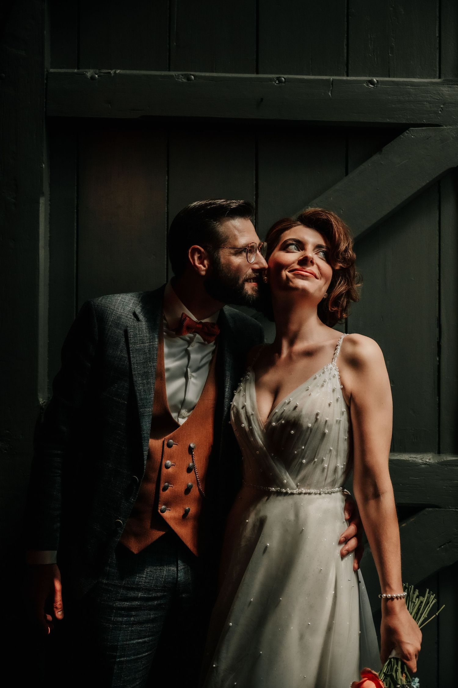 An intimate wedding portrait against a dark green wooden backdrop.