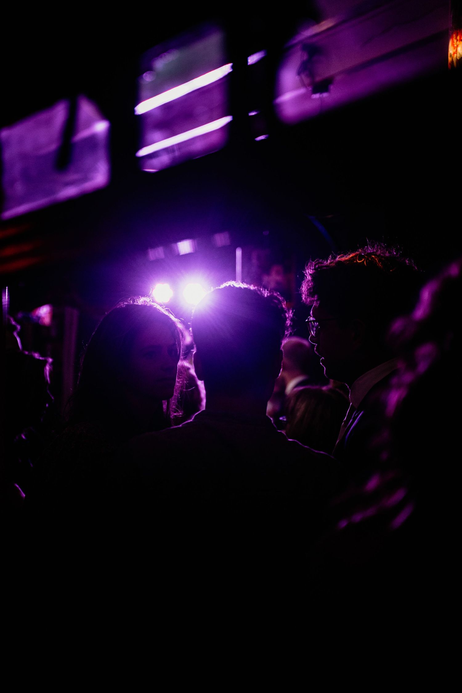 Dance floor illuminated with purple lighting creating silhouettes of party guests.