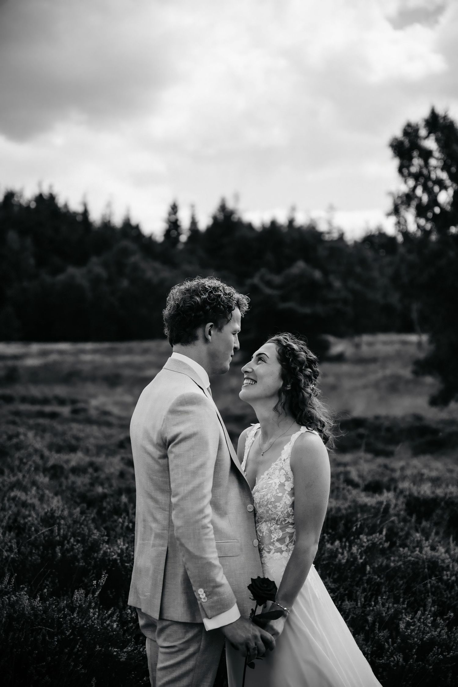 A romantic black and white portrait captured in a scenic outdoor field.
