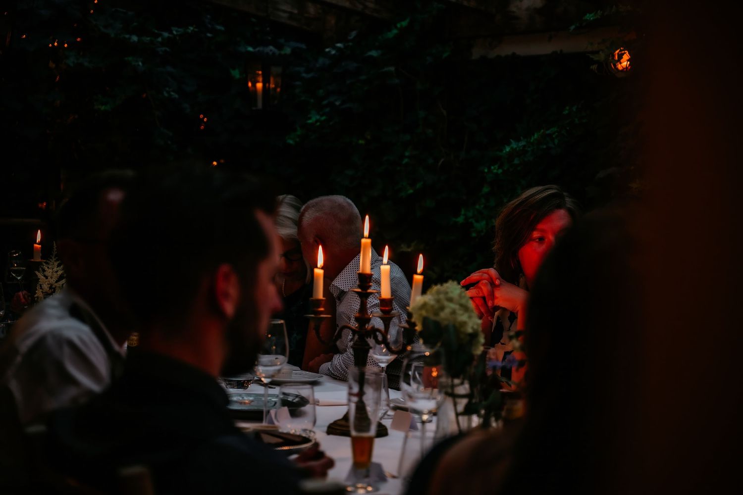 Candlelit wedding reception dinner with guests seated at long tables.