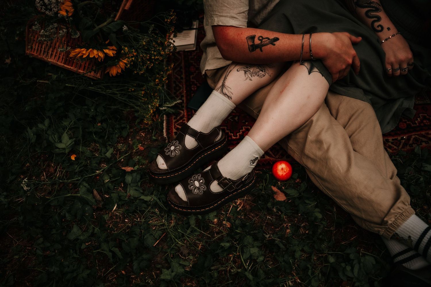 A person crouches in dark woods while photographing nature at night with glowing red lighting in the background.