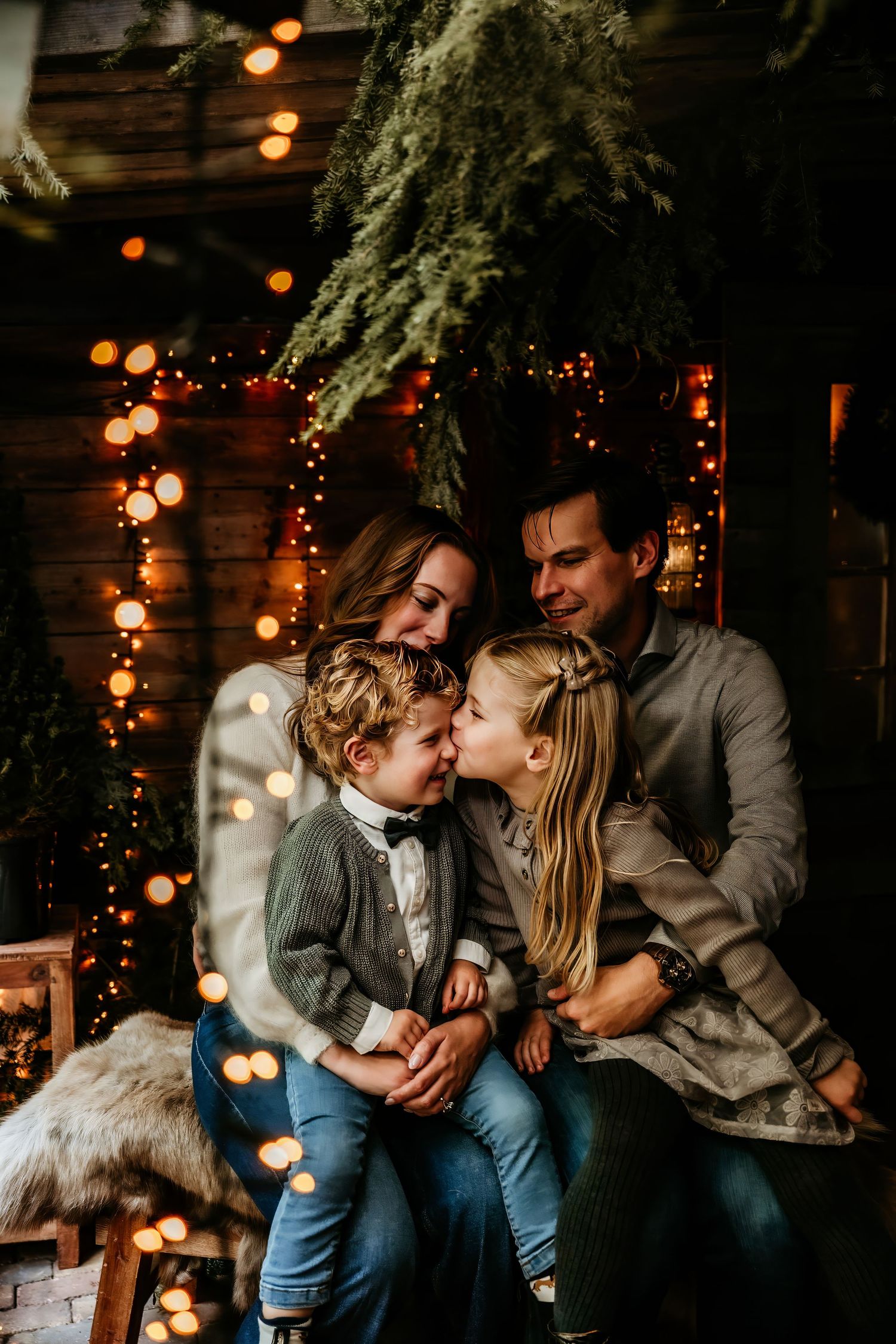 A cozy family portrait session with warm lighting and holiday decorations in a rustic indoor setting.