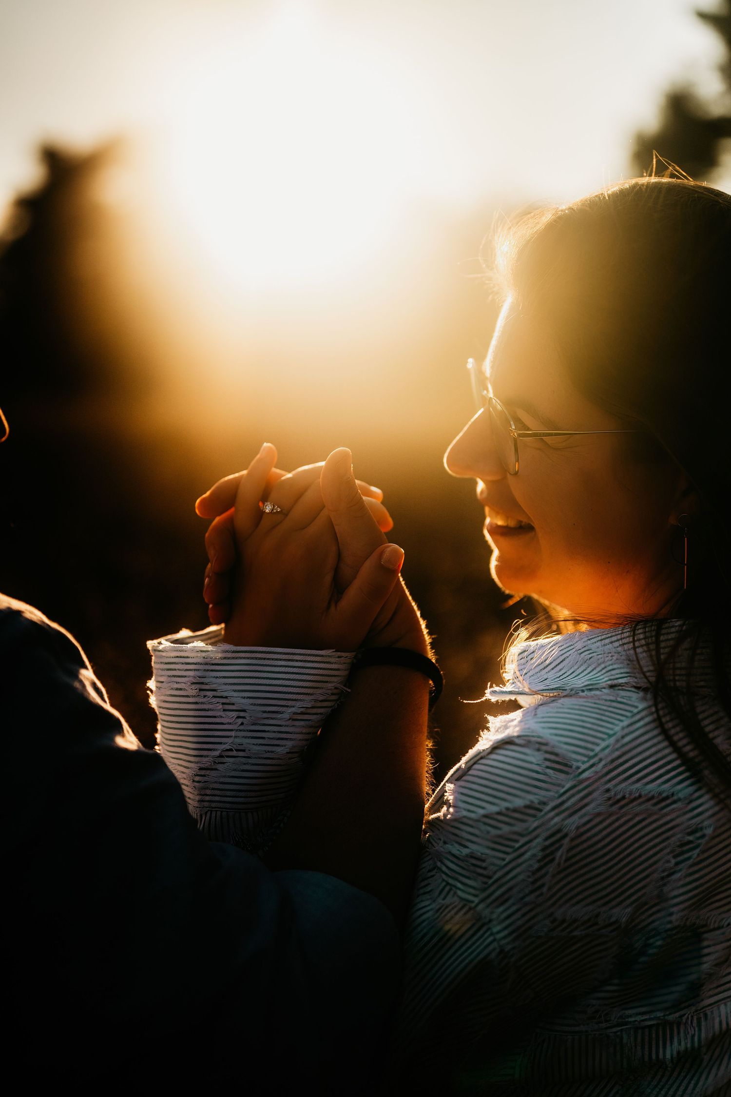 A person wearing a striped shirt is silhouetted against a warm sunset creating a dramatic backlit effect.