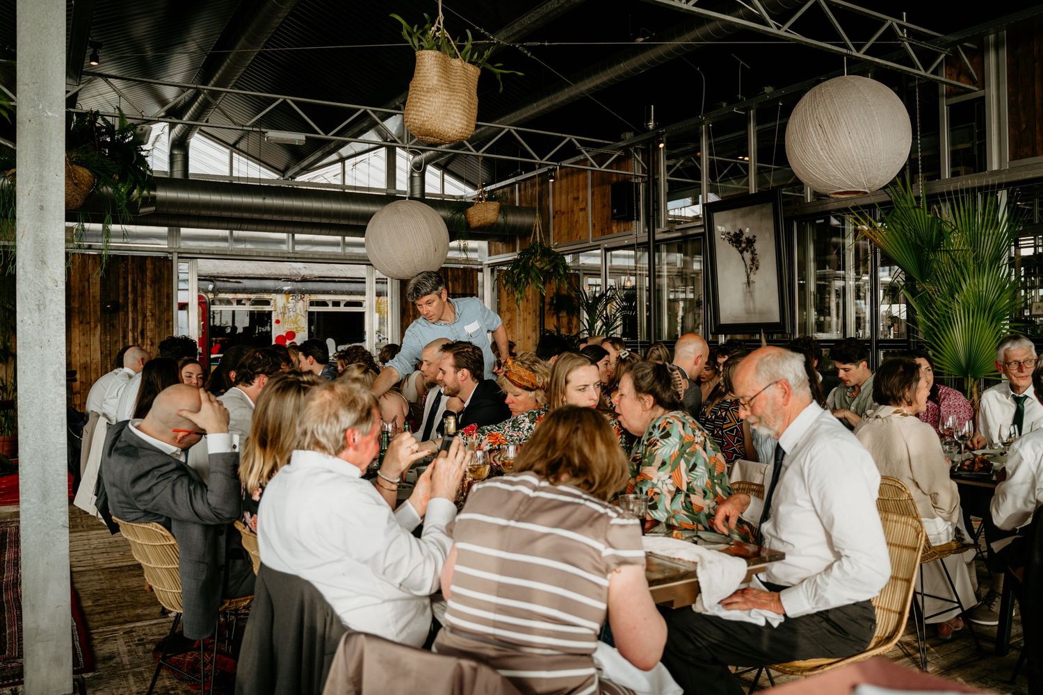 Wedding reception venue with hanging paper lanterns and guests seated at long tables.