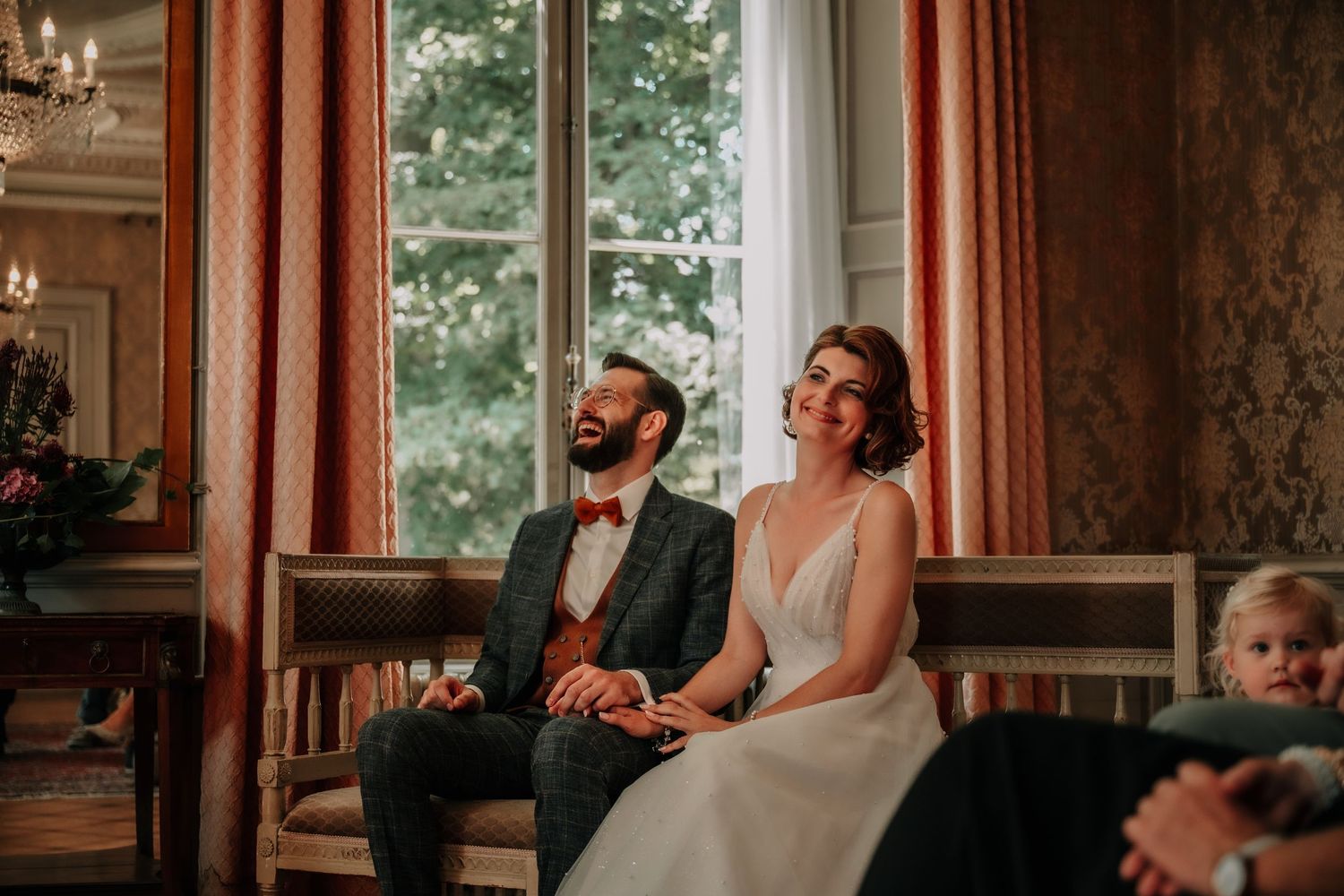 Elegant wedding celebration scene in a grand room with ornate windows and decor.