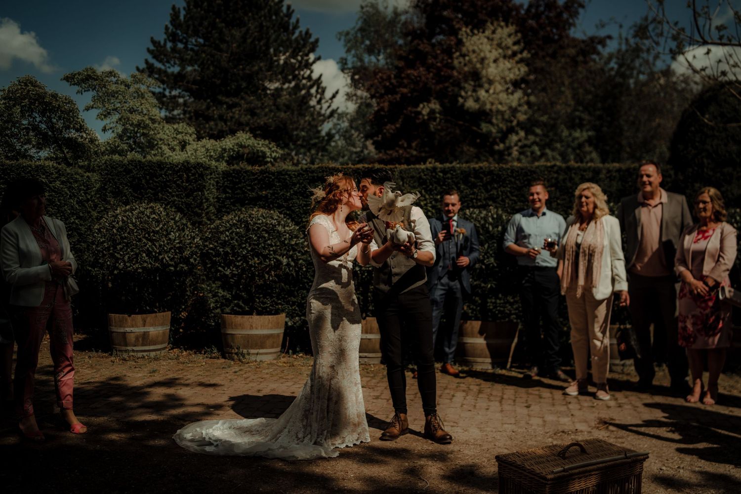 Wedding guests gather outdoors in a natural setting during golden hour sunlight.
