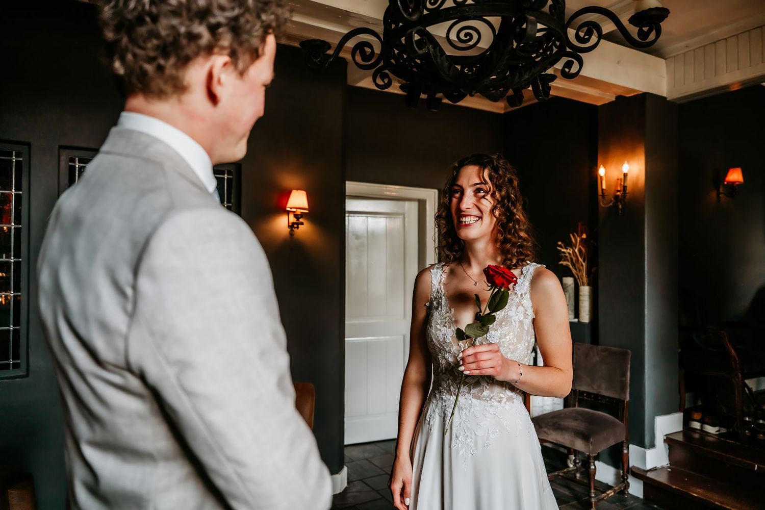 A couple shares an intimate moment during their first look at a dimly lit indoor venue with elegant decor.