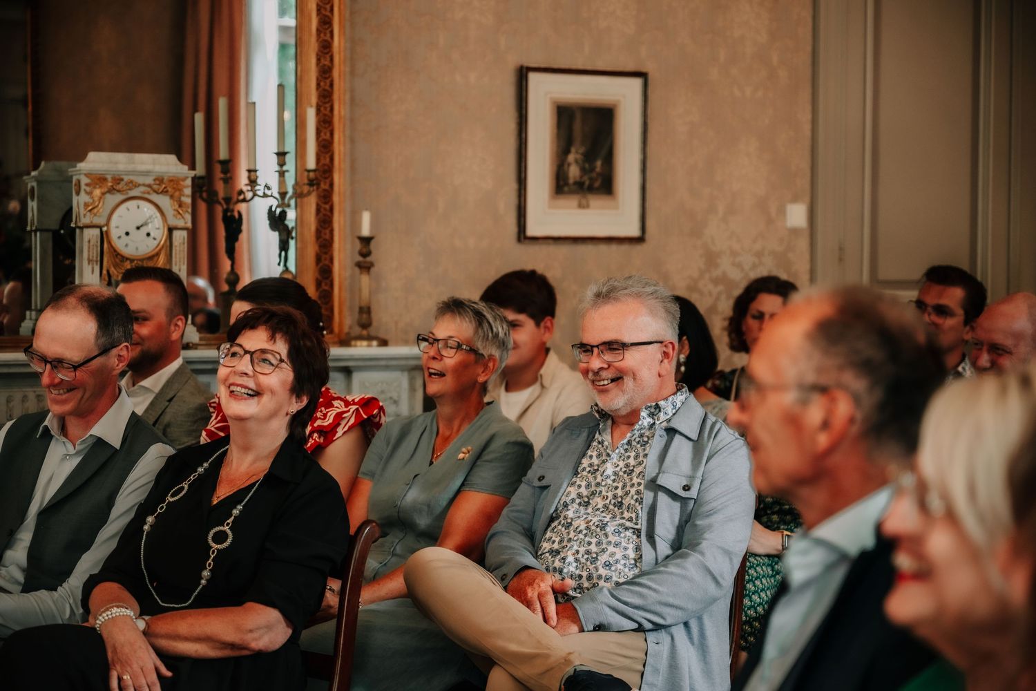 Wedding guests laugh and smile during a joyful reception celebration.