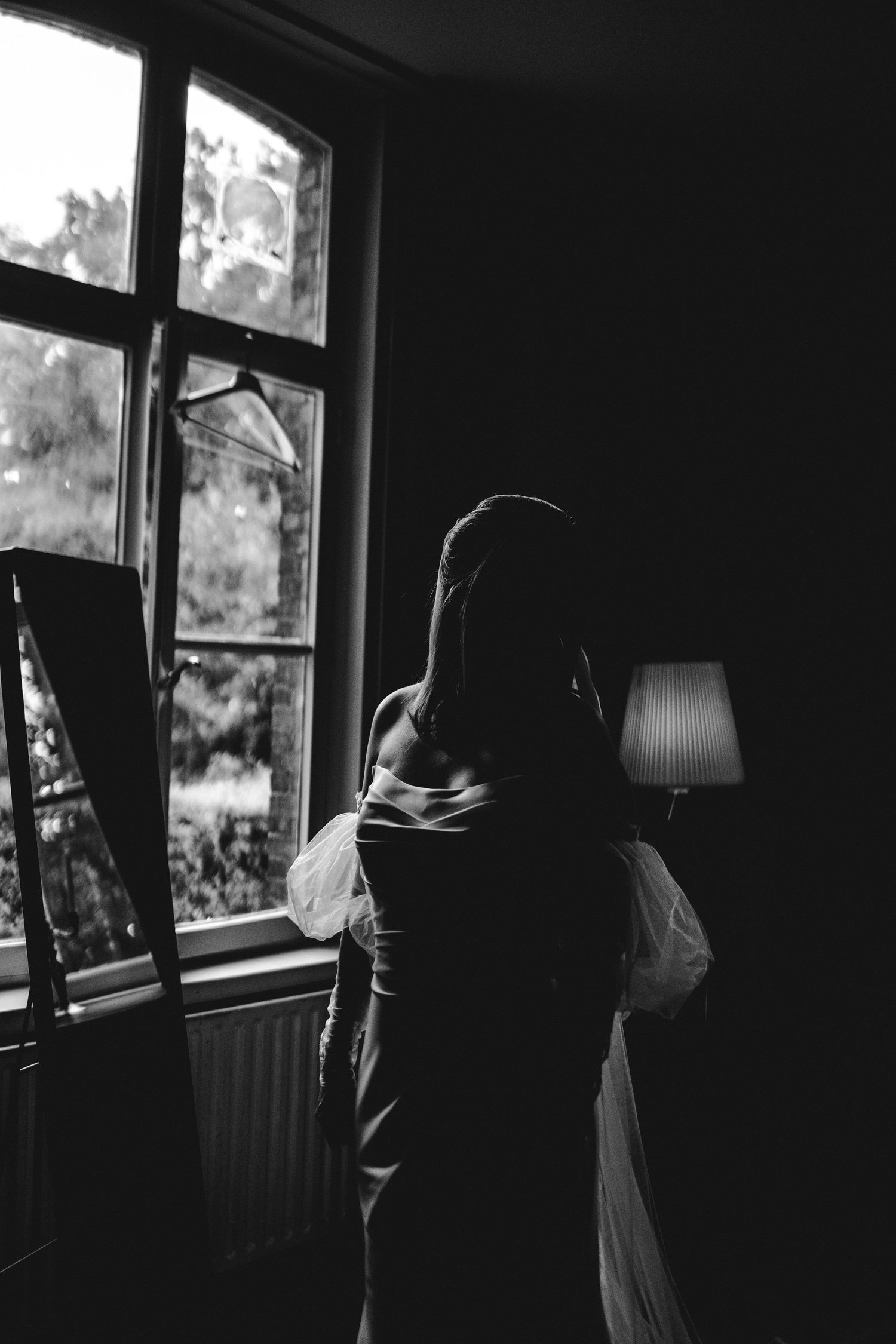 A moody black and white triptych showing silhouetted figures against bright windows in a dark interior space.