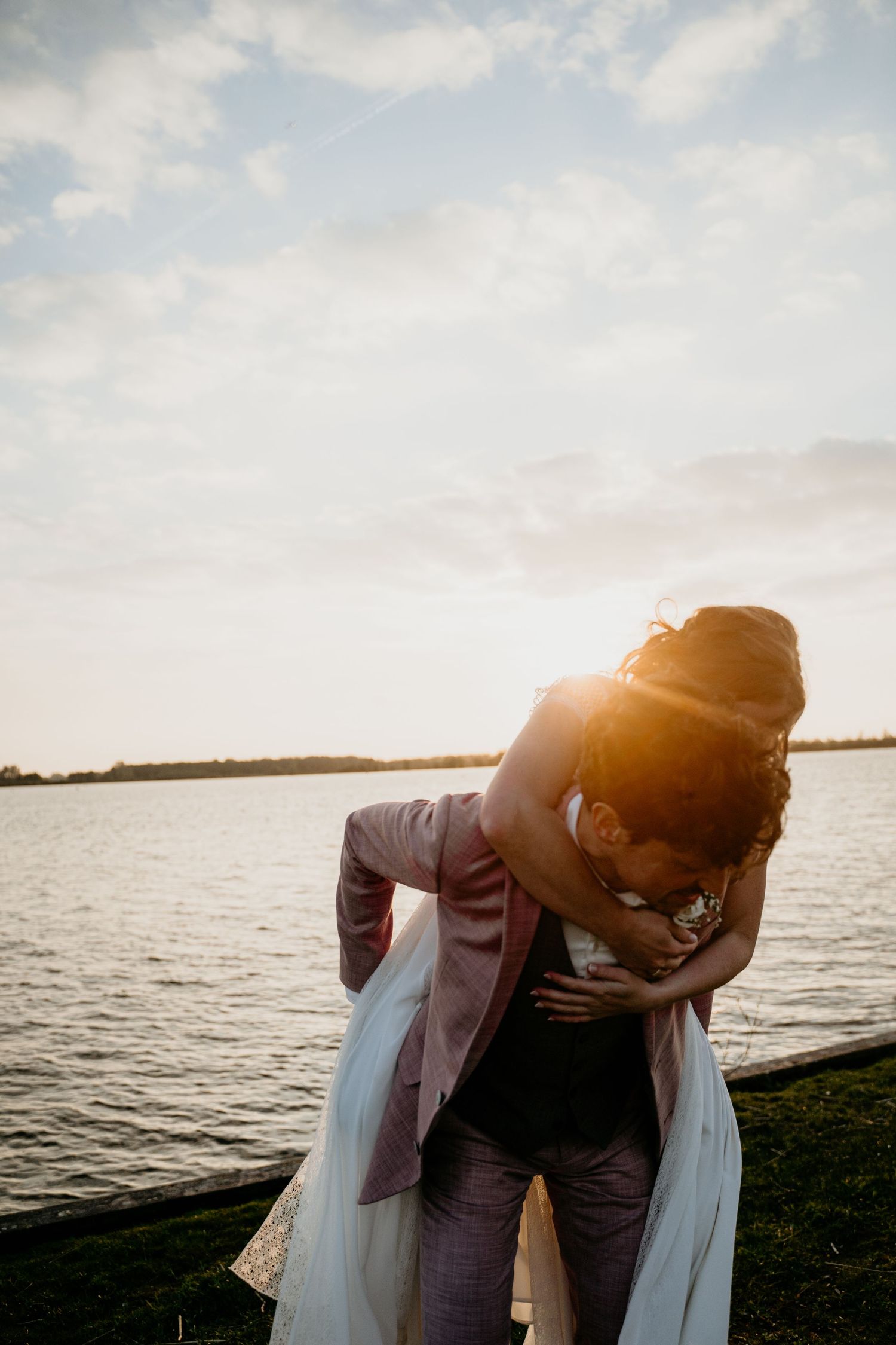 Intimate wedding couple portraits at sunset by the ocean with dramatic lighting.