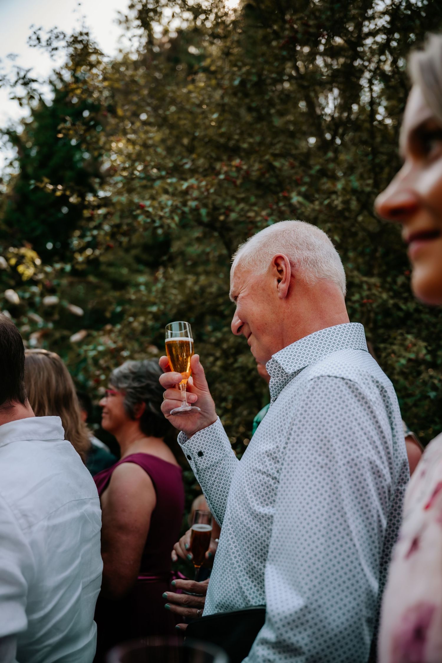 Wedding guests mingling during outdoor cocktail hour in garden setting.