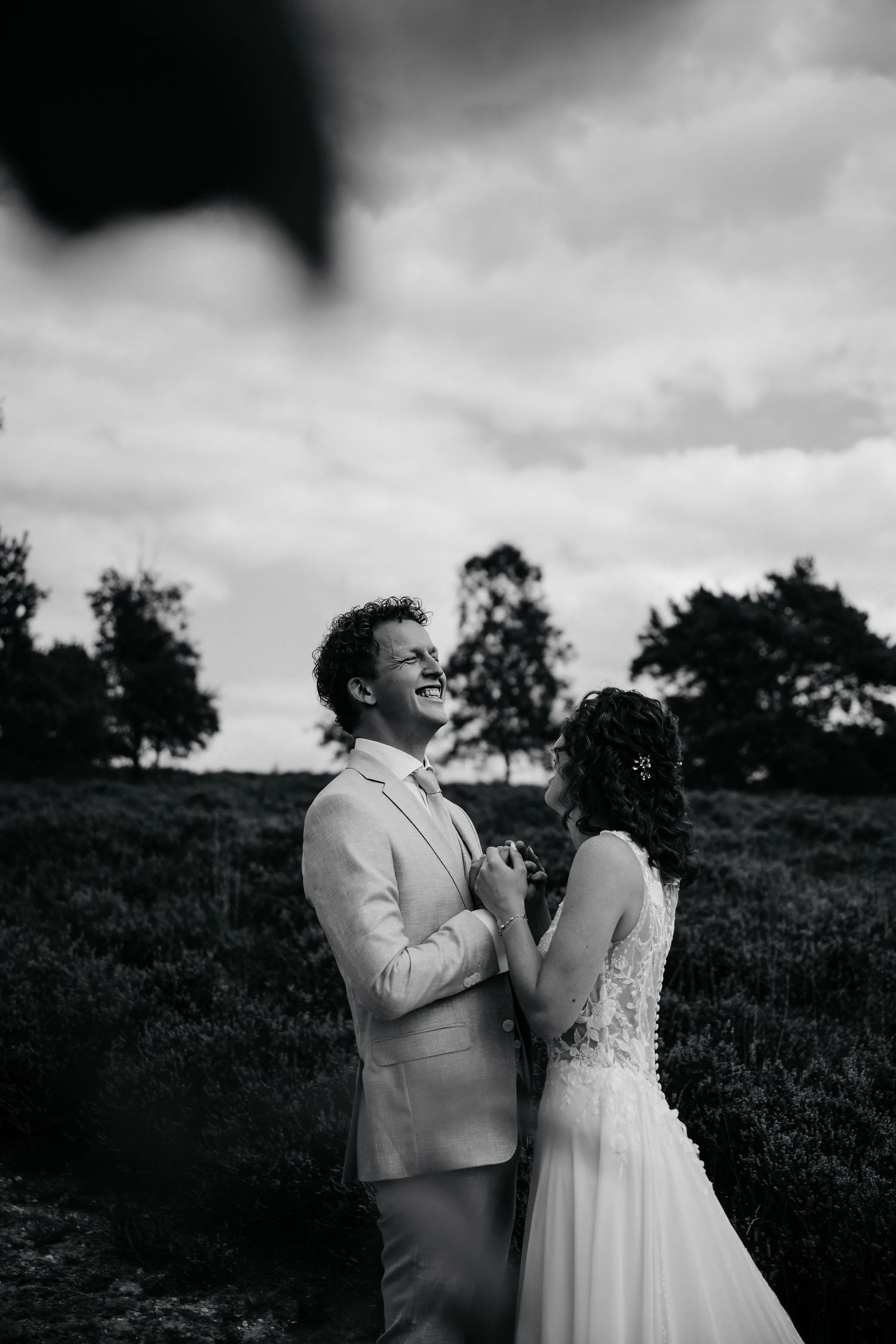 An intimate black and white moment shared between a couple in formal attire outdoors.