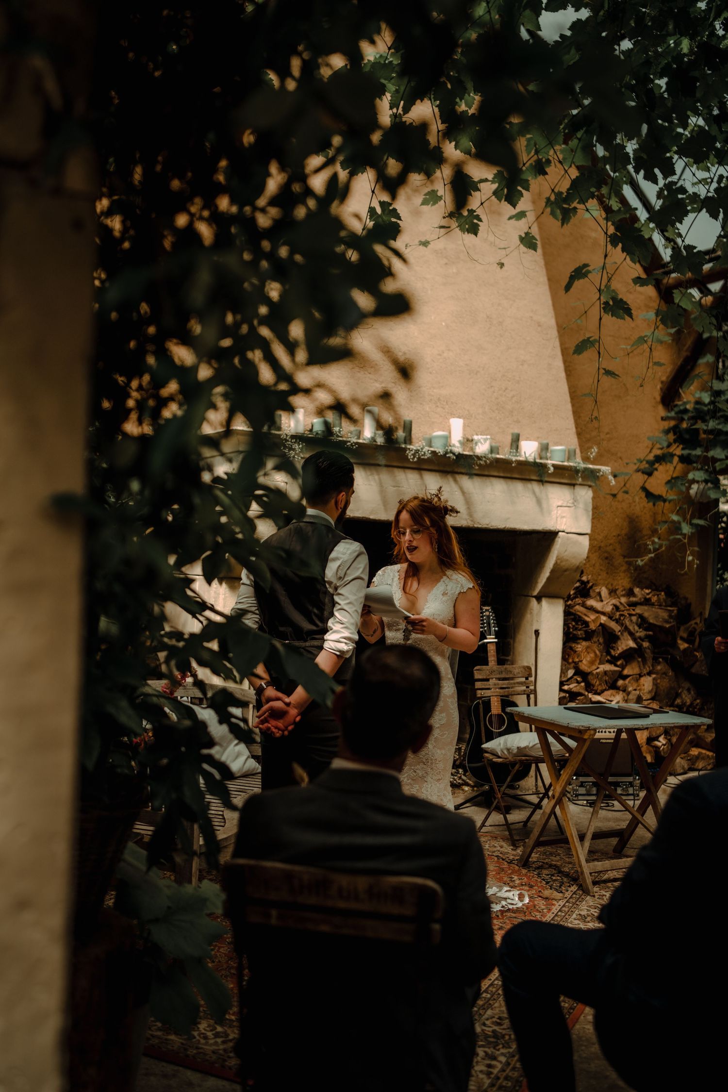 Intimate outdoor garden wedding ceremony with guests gathered under leafy trees.